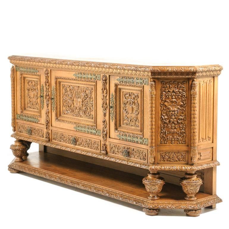 Solid oak, hand-carved, 20th century Renaissance-Revival buffet or sideboard. Impressive carving and detailed brass accents. Has an oak-framed 10? lower shelf for additional storage. A beautiful piece.

     