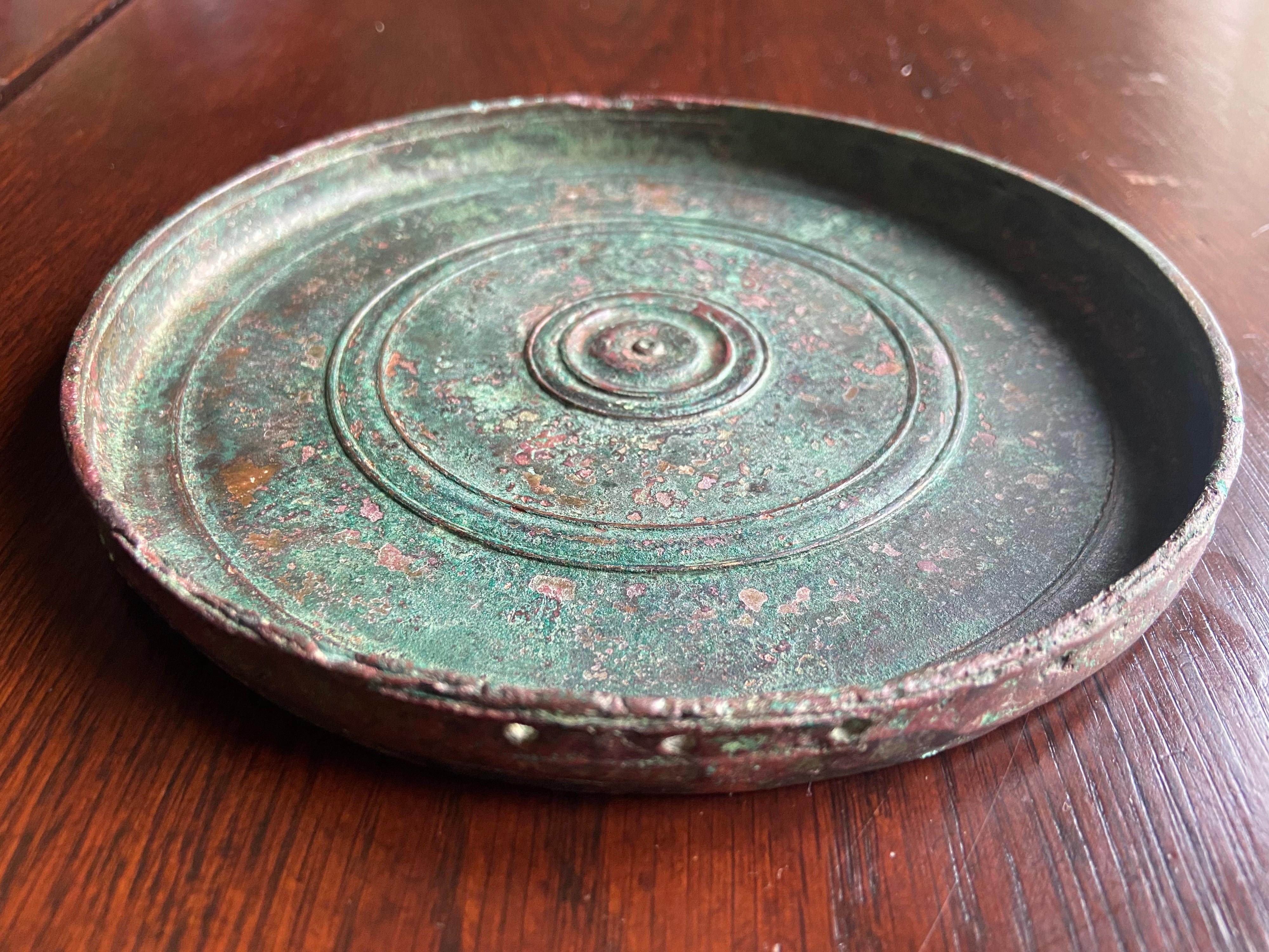 Highly decorated ancient Roman round bronze hand mirror in very good condition with lovely patina without a cover.
Possibly there was a held attached to it but now only the three small halls are visible. Measure: 16 cm.

Highly decorated ancient