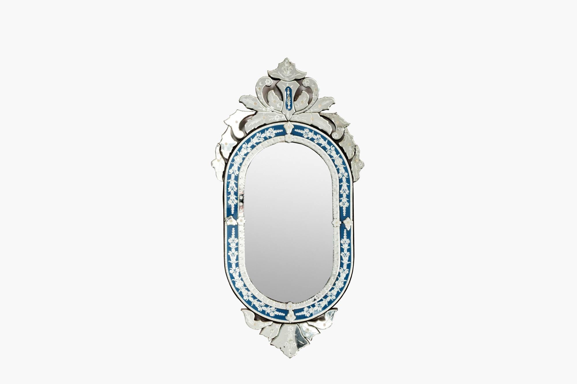 A highly decorative late 19th century Venetian glass mirror with reverse etched patterning and detailed hand painted enamelled blue glass panels. The central bevelled plate within the decorative frame beneath an exuberant scrolled crest with a