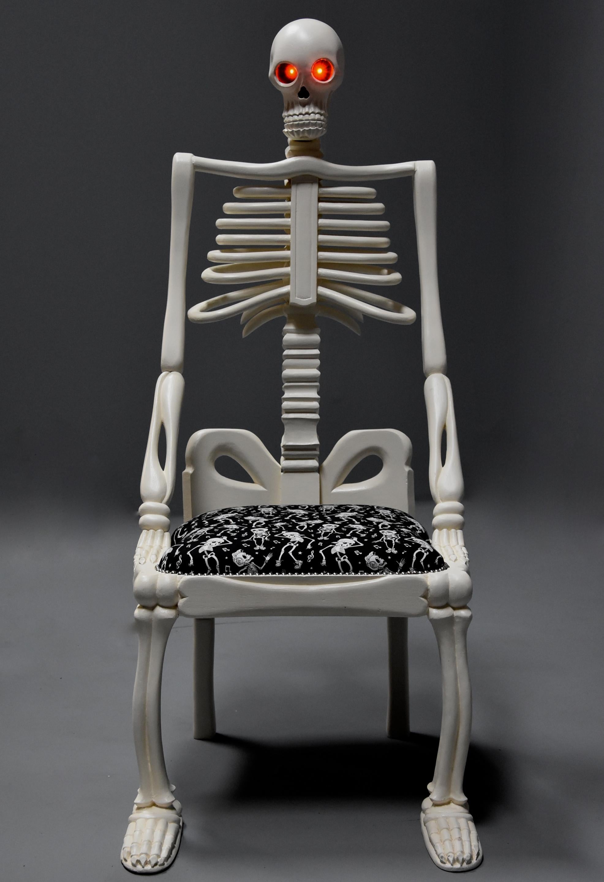 Highly decorative and unusual hand-carved and painted wooden skeleton chair.

This quirky chair consists of a hand carved and painted wooden chair in the form of a skeleton, the skull head having LED lights in the eye sockets that illuminate with