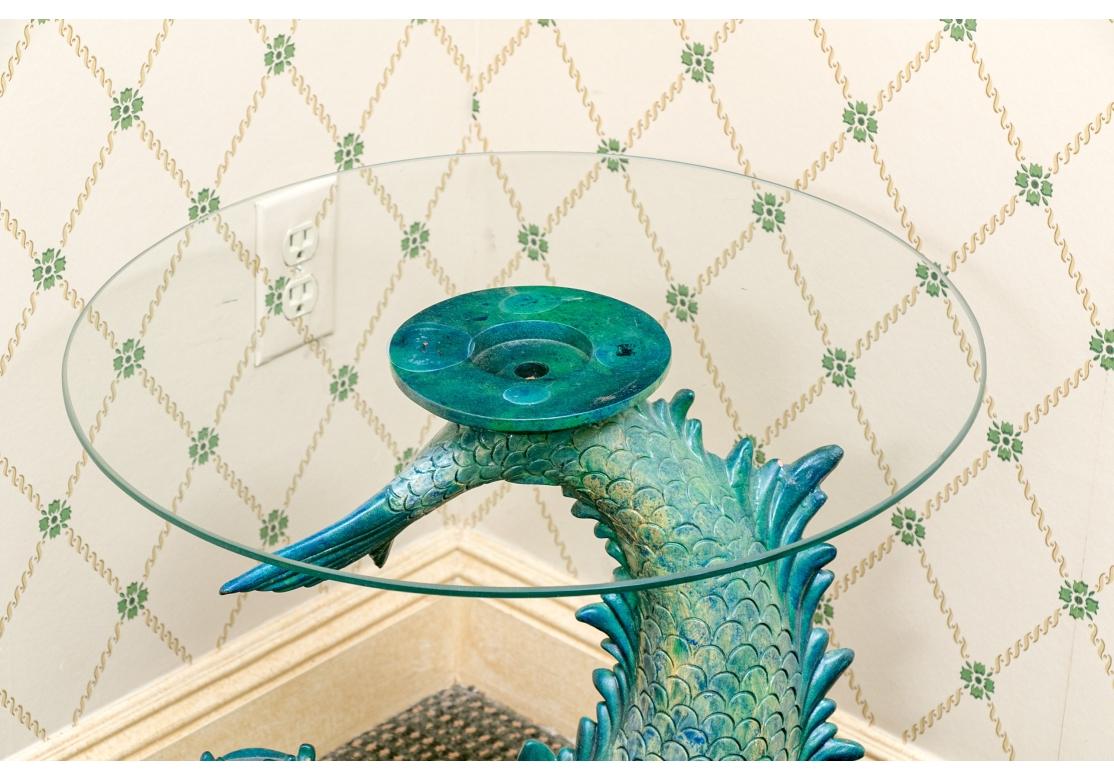 Vintage glazed terracotta dolphin table, in the Hollywood Regency style, surmounted with a fixed glass top. The base is a single, large terracotta sculpture of a mythical sea creature (grotesque dolphin or fish) with a distinct blue-green verdigris