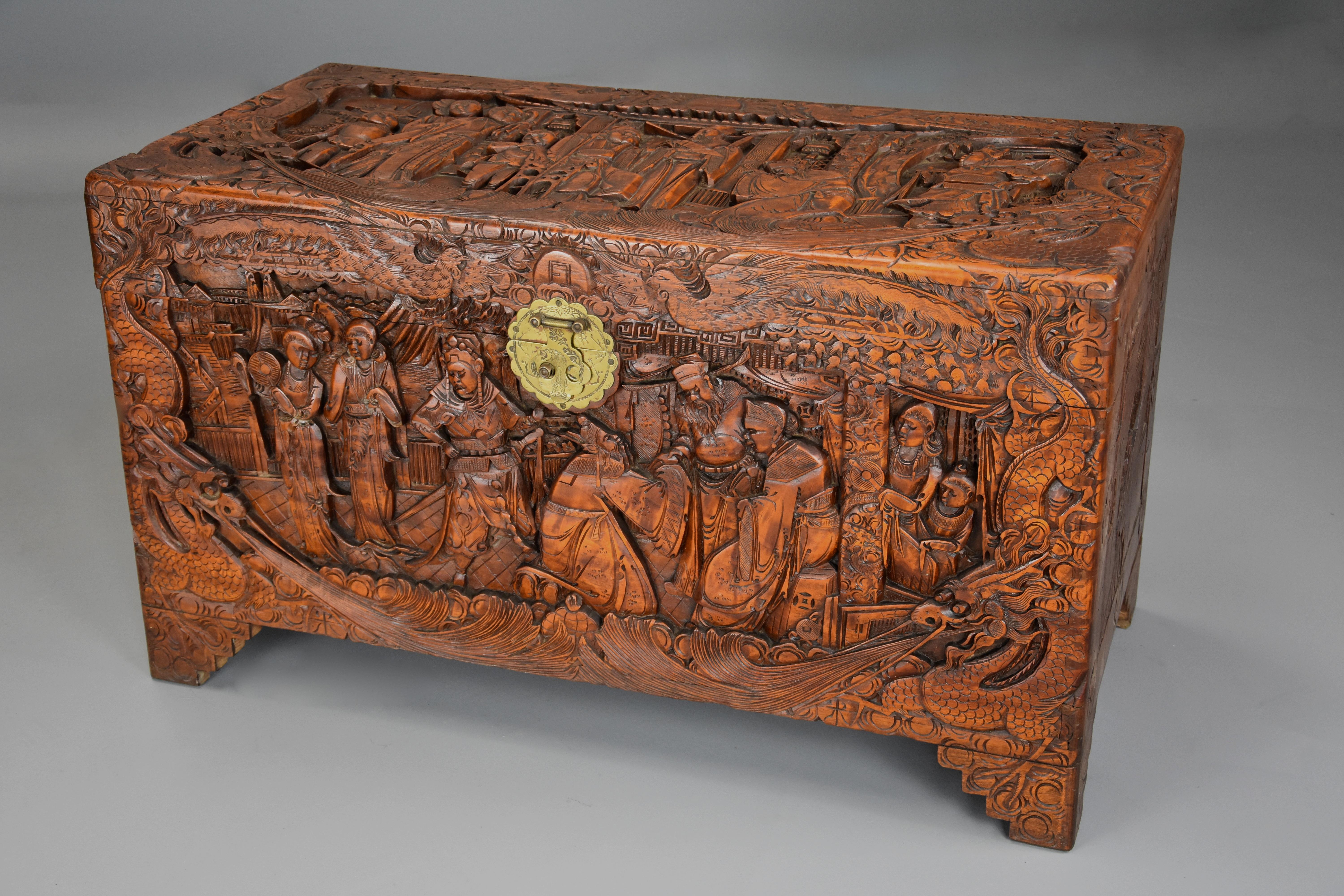A highly decorative mid-20th century profusely and deep carved Eastern camphor wood freestanding chest or trunk. 

This camphor chest consists of a superbly carved top depicting traditional Oriental scene with a border of carved dragon and bird