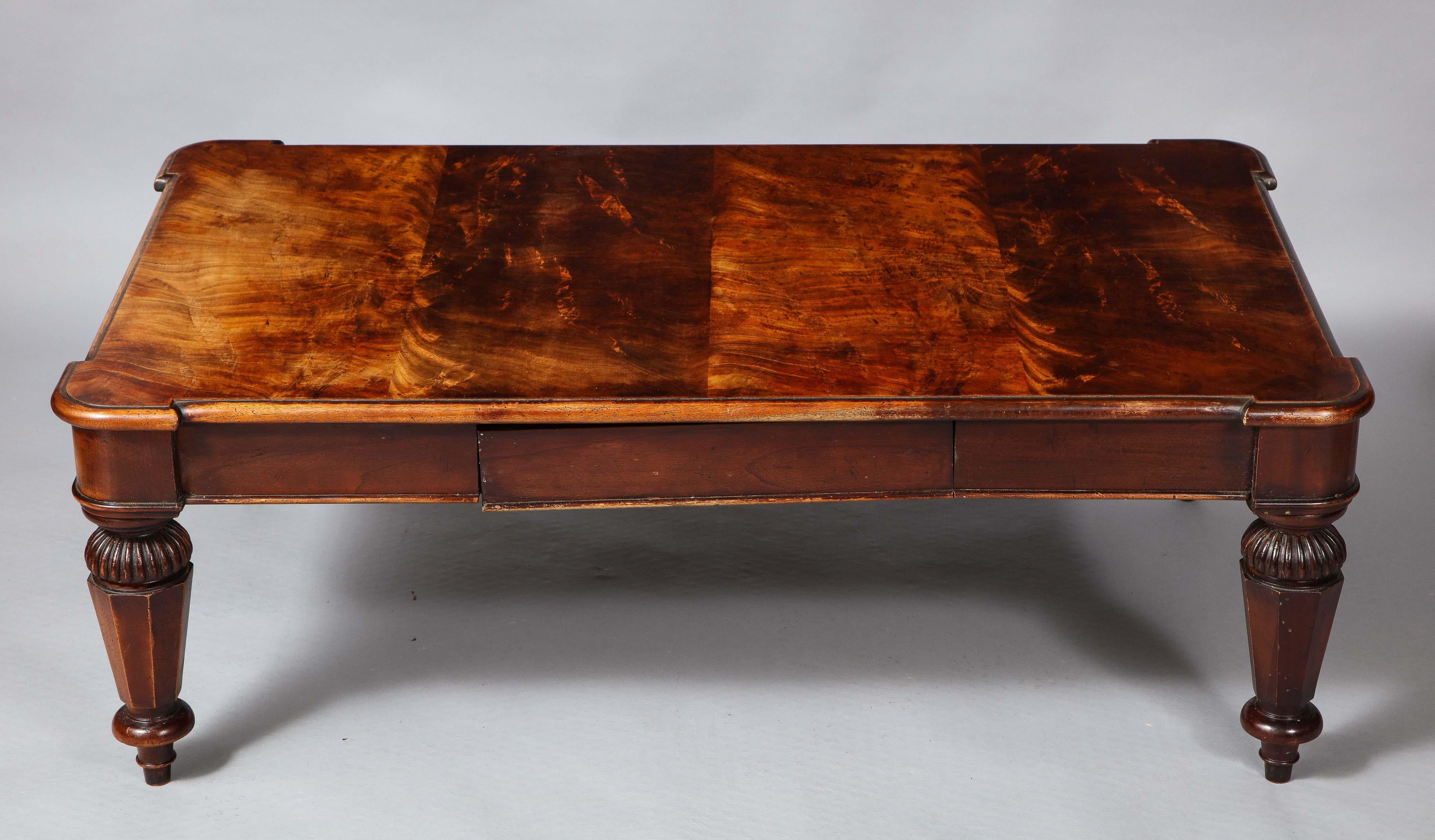 Good mid-20th century mahogany coffee table in the manner of George Smith having highly figured top with thumb molded edge over single-drawer, the turned legs with fluted collars and tapering octagonal mid sections and ending in turned feet.