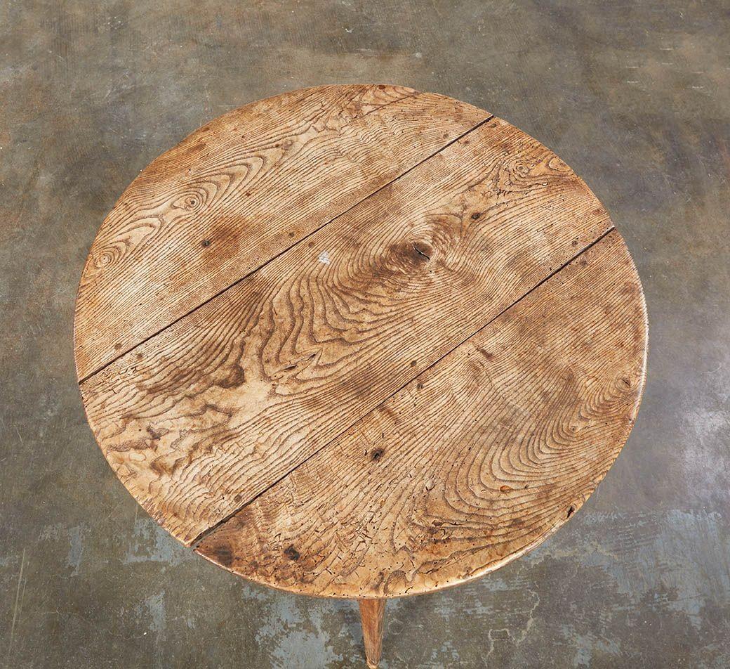 A Welsh cricket table having round plank top over three legs with lovely mellow and highly figured pale elm three plank top over ash base. Great size next to a sofa for a table lamp. Called a cricket table after the Welsh word for hearth, and