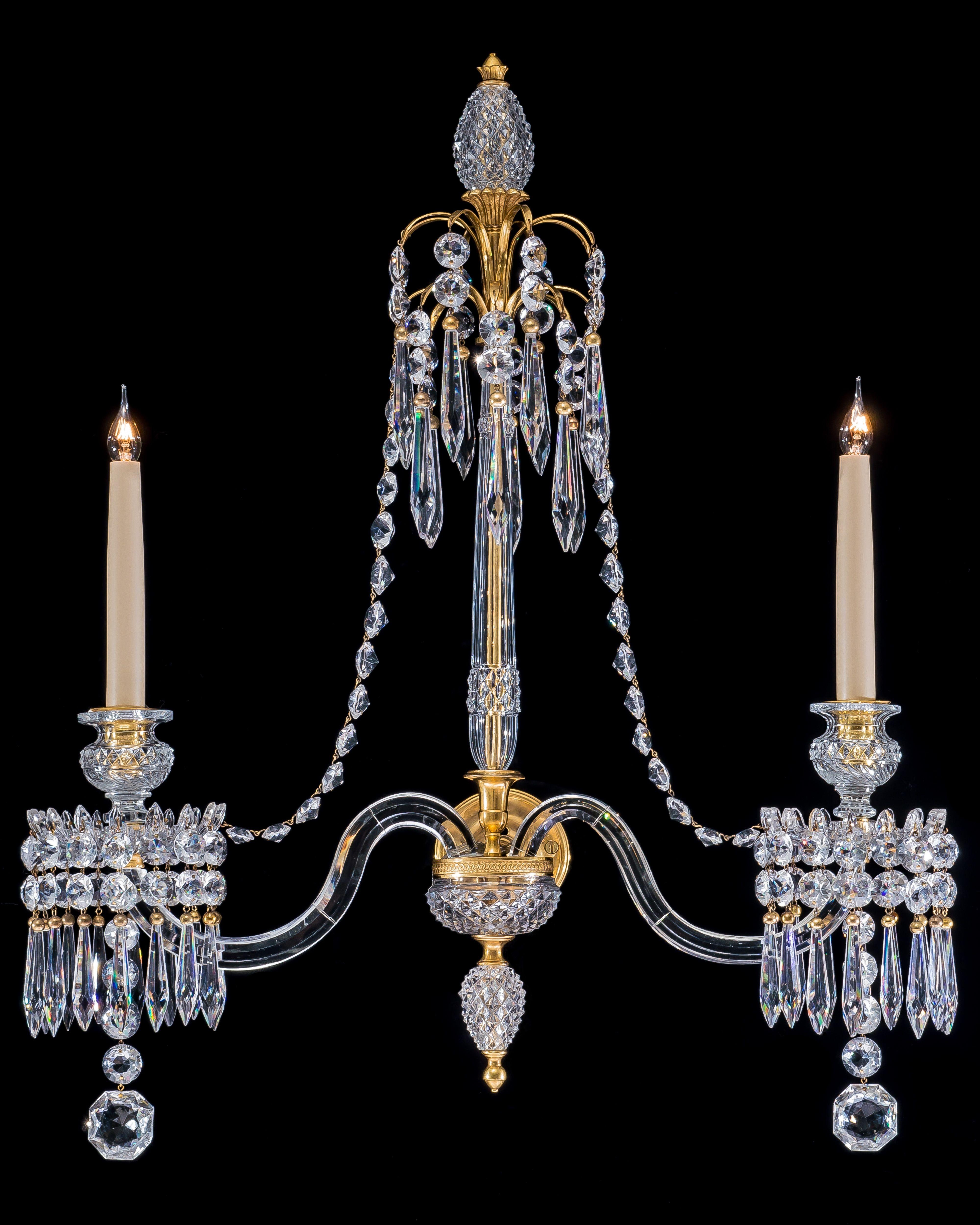 A highly important pair of George III cut-glass ormolu-mounted wall lights the central diamond and slice cut shaft surmounted by two gilt fountain sprays hung with ormolu capped icicle drops and flat back spangles the shaft terminating with a