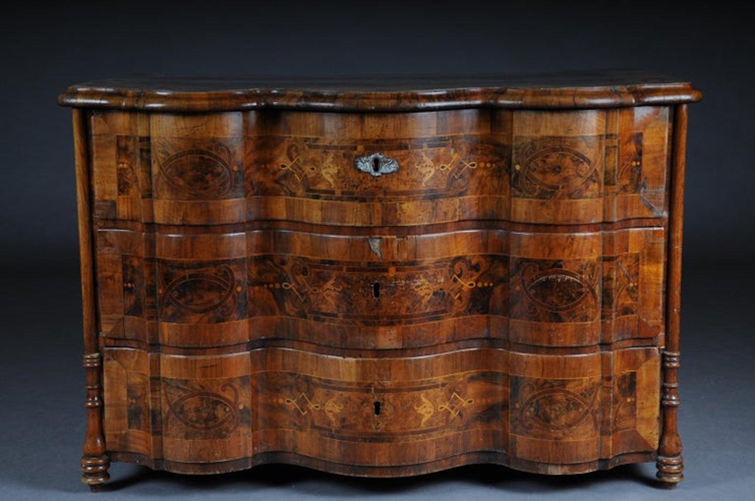 Highly interesting inlaid Baroque commode, circa 1740

Various fine wood veneers on solid fir wood. Profile framed, reasonably curved frame on pressed ball feet. Just 3 Schübiger, strongly curved in the front body. Sides and cover plate with inlaid