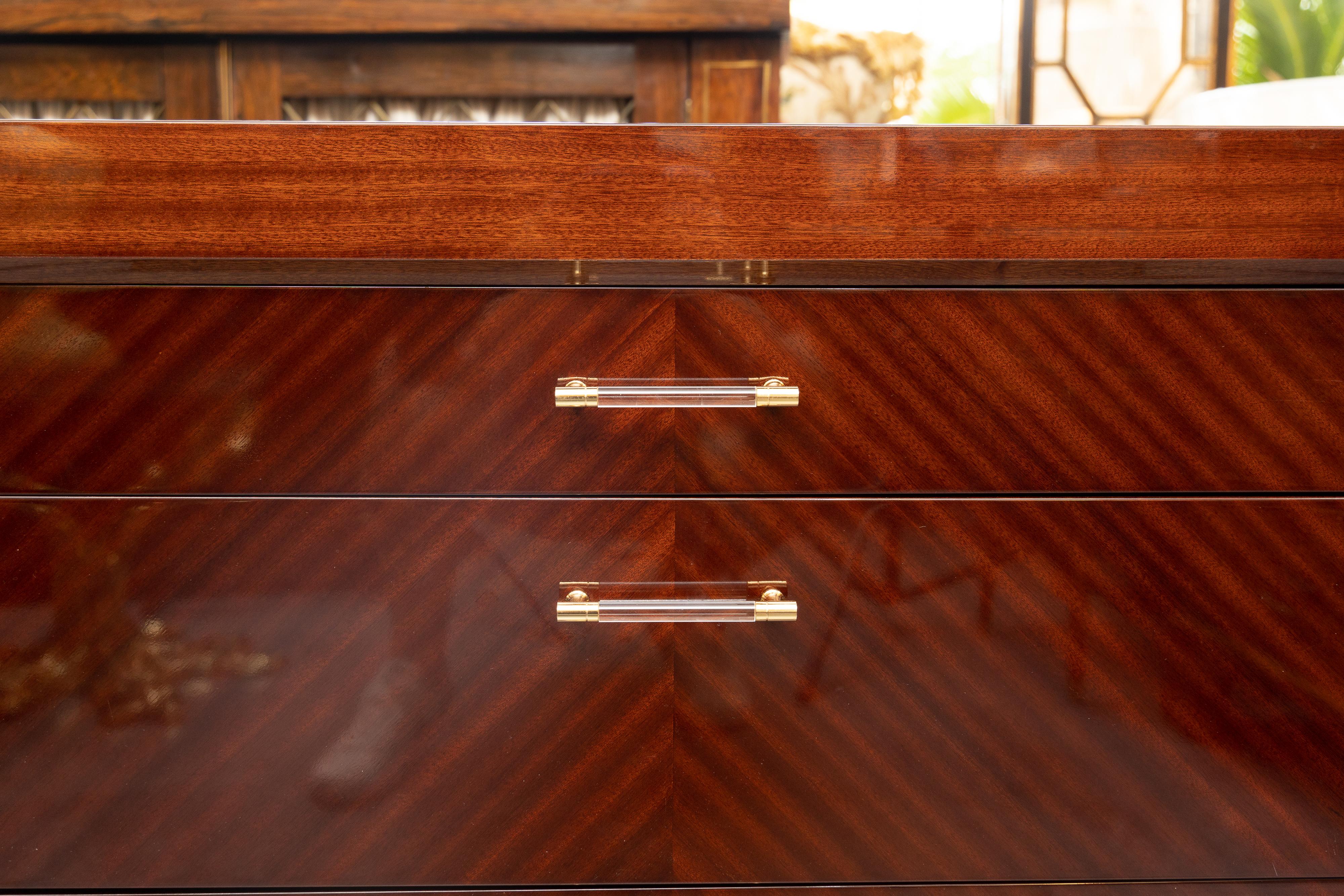 A spectacular, highly polished midcentury chests of drawers. The drawers are graduated from narrow to a wide drawer are the bottom. Bench made. Lucite and brass handles. Pair available. Priced individually.