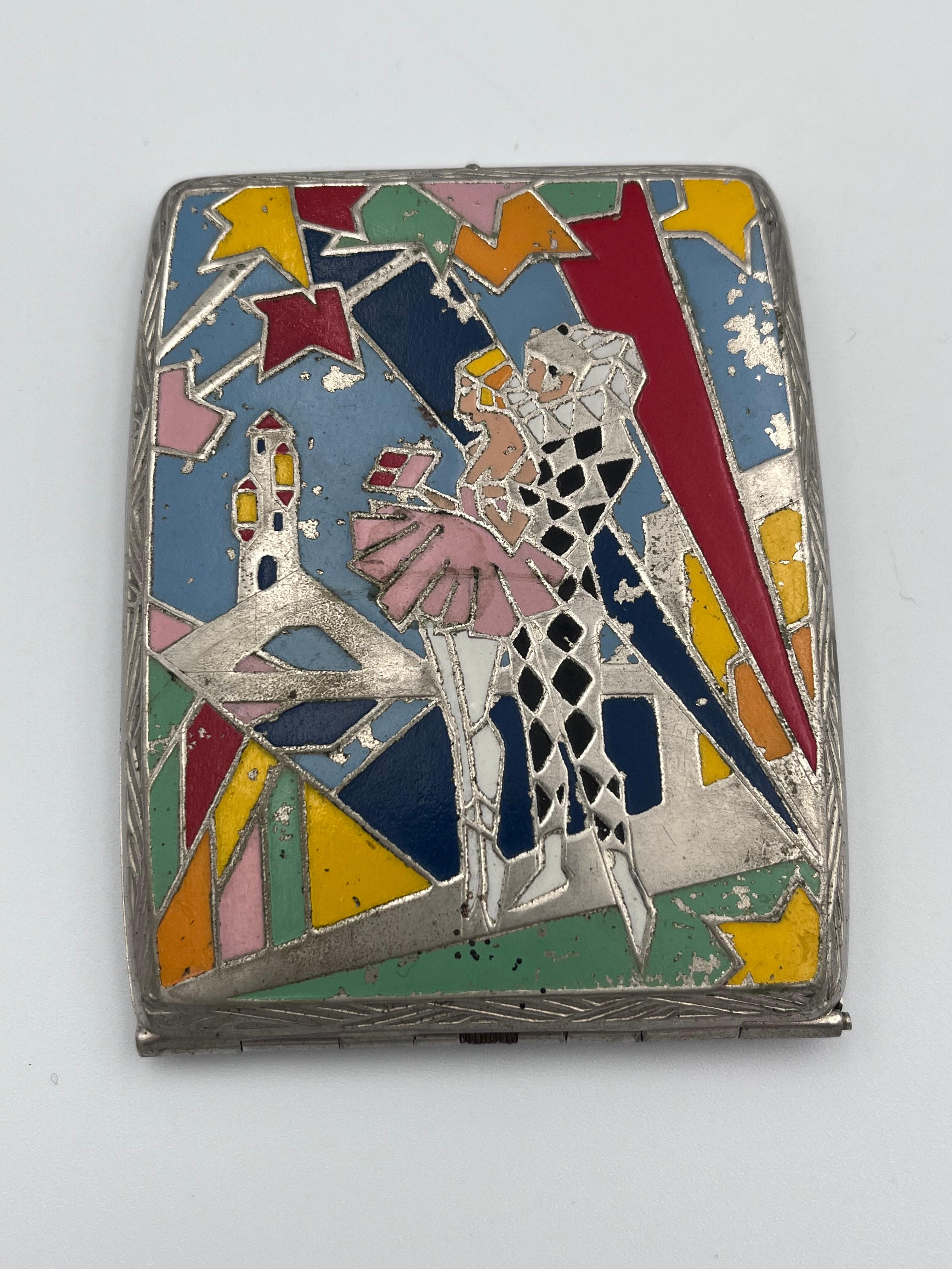 Cet étui à cigarettes Art déco très inhabituel des années 1930 présente une scène fantastique en métal et en émail en relief. Un arlequin classique, aux formes géométriques et cubistes, est représenté avec un grand col à volants et une tenue à