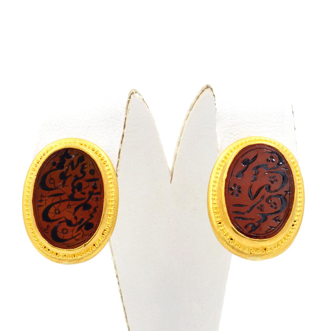 Here is a beautiful pair of 24 karat yellow gold earrings designed by the jewelry designer Hilat.  This pair of earrings feature a cinnamon colored agate carved with arabesque designed and enameled with black enamel.  The earrings are finished with
