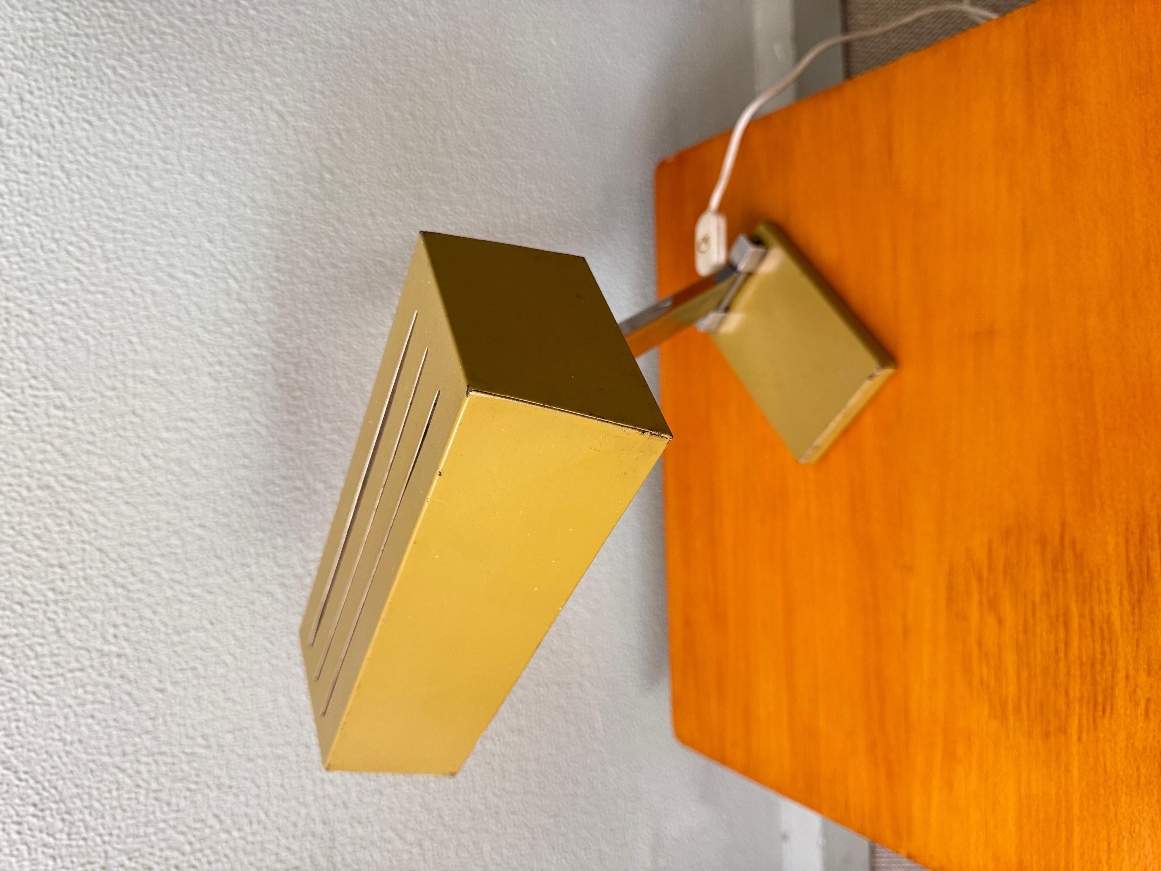 This striking table lamp, designed by Hilbrand in the 1970s, is a bold example of geometric modernist lighting. Its sculptural form is defined by a sharply angled rectangular shade in mustard-yellow lacquered metal, mounted on a chrome-plated steel