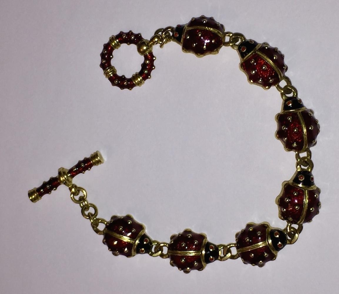 18 karat yellow gold lady bug bracelet with red and black enamel. Measures 7.5” long by 0.75” wide. Marked, Hidalgo, 750. Closes with large jump ring and t-bar. Weighs, 35.1 grams
