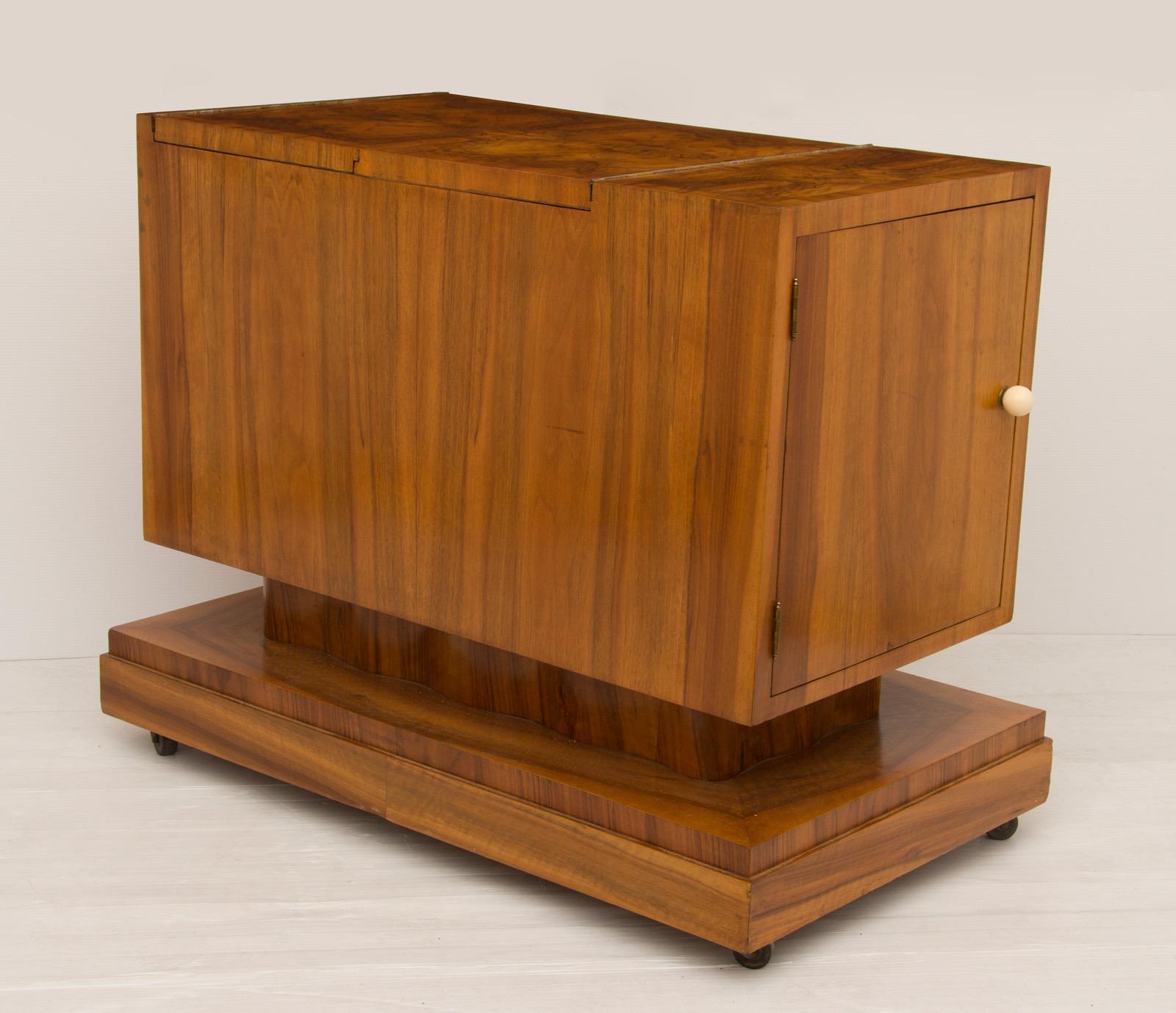 Beautiful Art deco bar cabinet by Hille
Stunning burr walnut bar cart on casters.
Side section has storage for bottles, the top section folds over to reveal the fitted interior and the front panel folds down and has a mirrored top for serving and