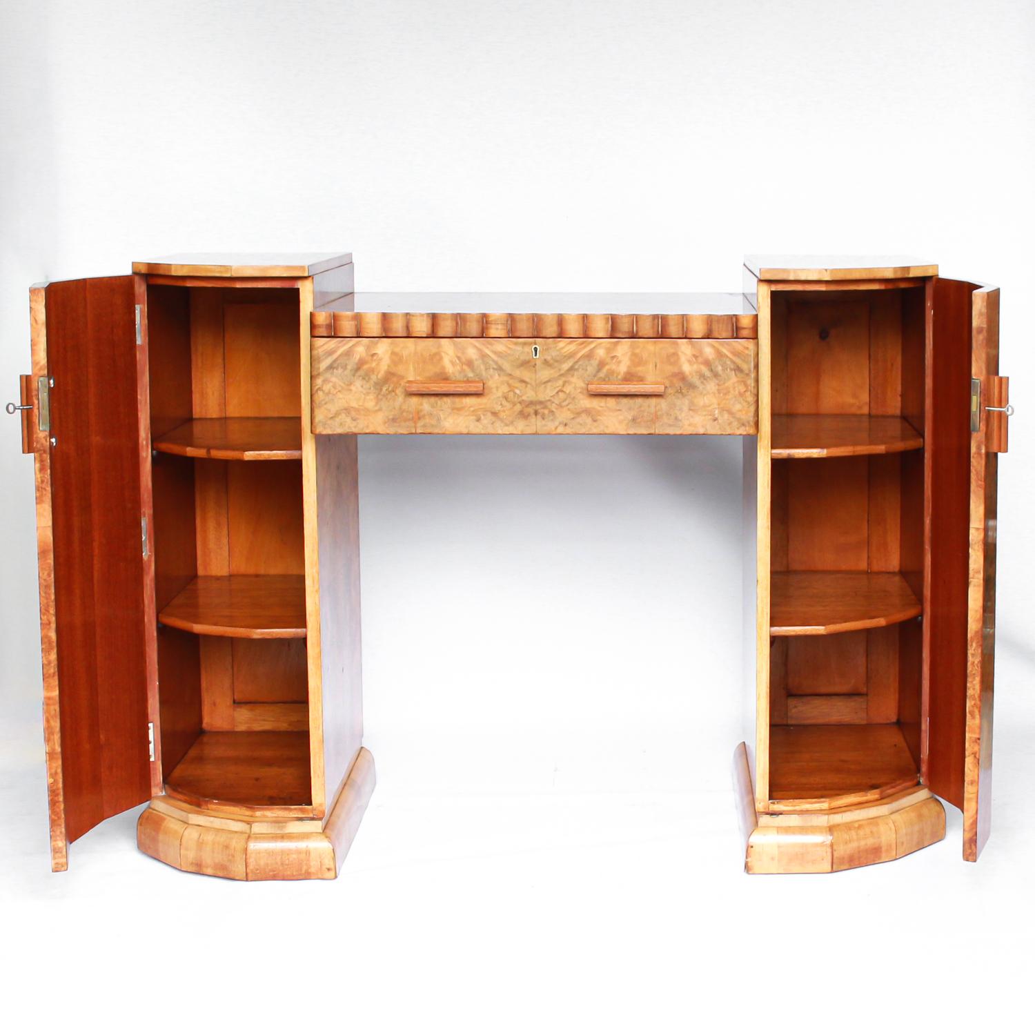 An Art Deco console sideboard by Hille. Burr walnut veneer throughout. Scallop-edged detail to front with integral drawer. Shelved cabinets to either side.

Dimensions: H 97cm, W 129cm, D 46cm

Origin: English

circa 1930



   