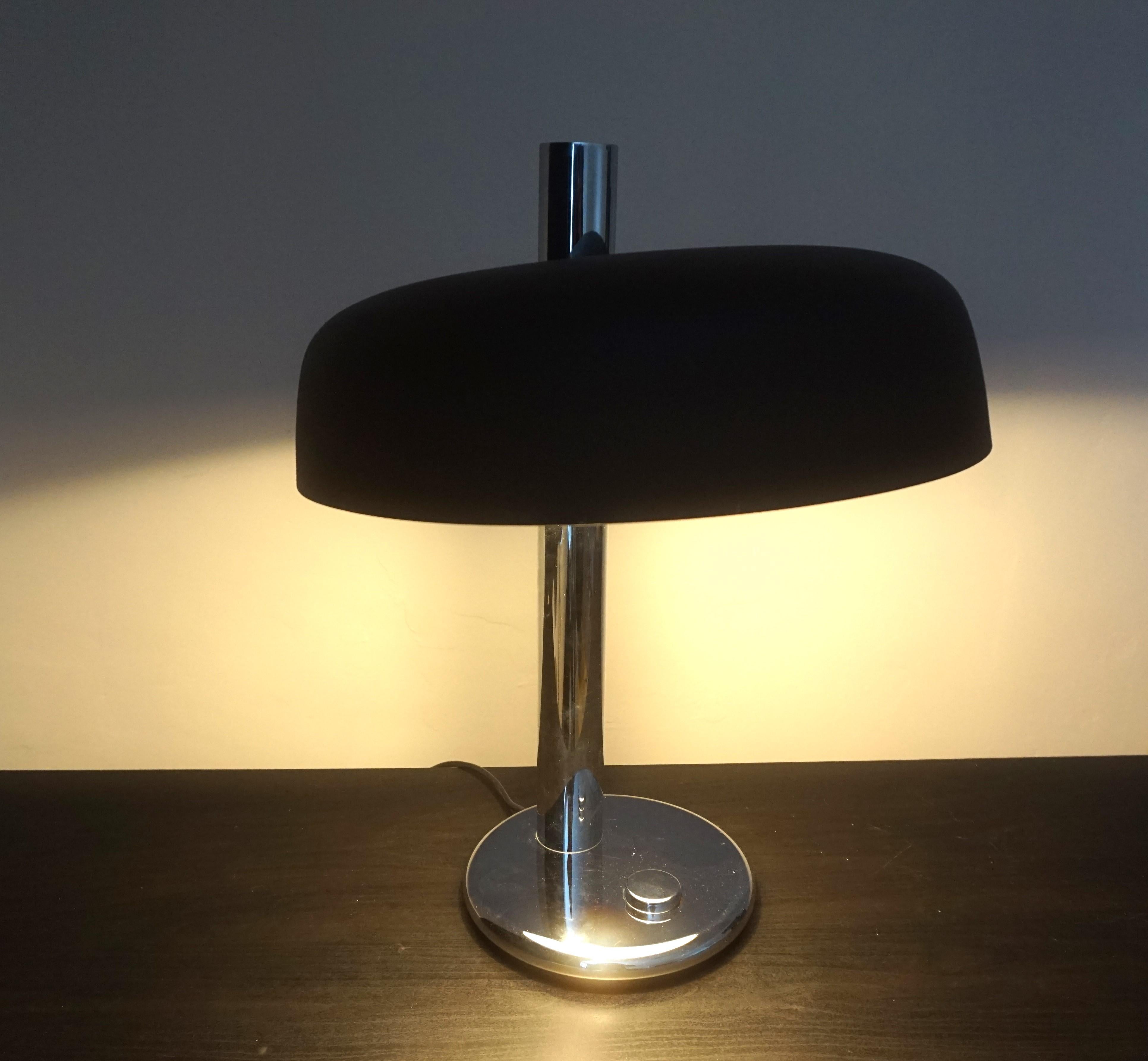 The large table lamp in the more elegant version with a chrome base and brown lampshade is in good condition. The base shows almost no signs of use, the brown metal shade shows signs of wear on one side. The large switch button works perfectly, the