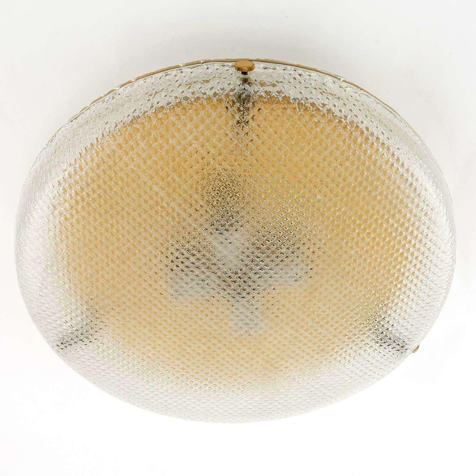 A wonderful light fixture by Hillebrand, Germany, manufactured in midcentury, circa 1970 (late 1960s or early 1970s). 
It can be used as wall or ceiling lamp. A round textured glass with a grid pattern is mounted with three brass bolts on a