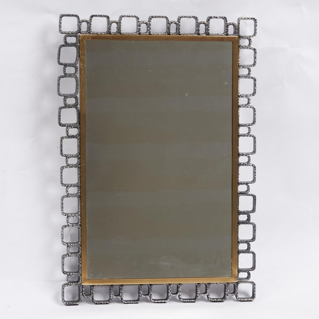 A Mid-Century wall mirror with a frame constructed of cast metal sculptural elements in the “Brutalist” aesthetic. The frame surrounds a polished and lacquered brass inner frame. This model was produced by 'Hillebrand' in the 1970's. A very