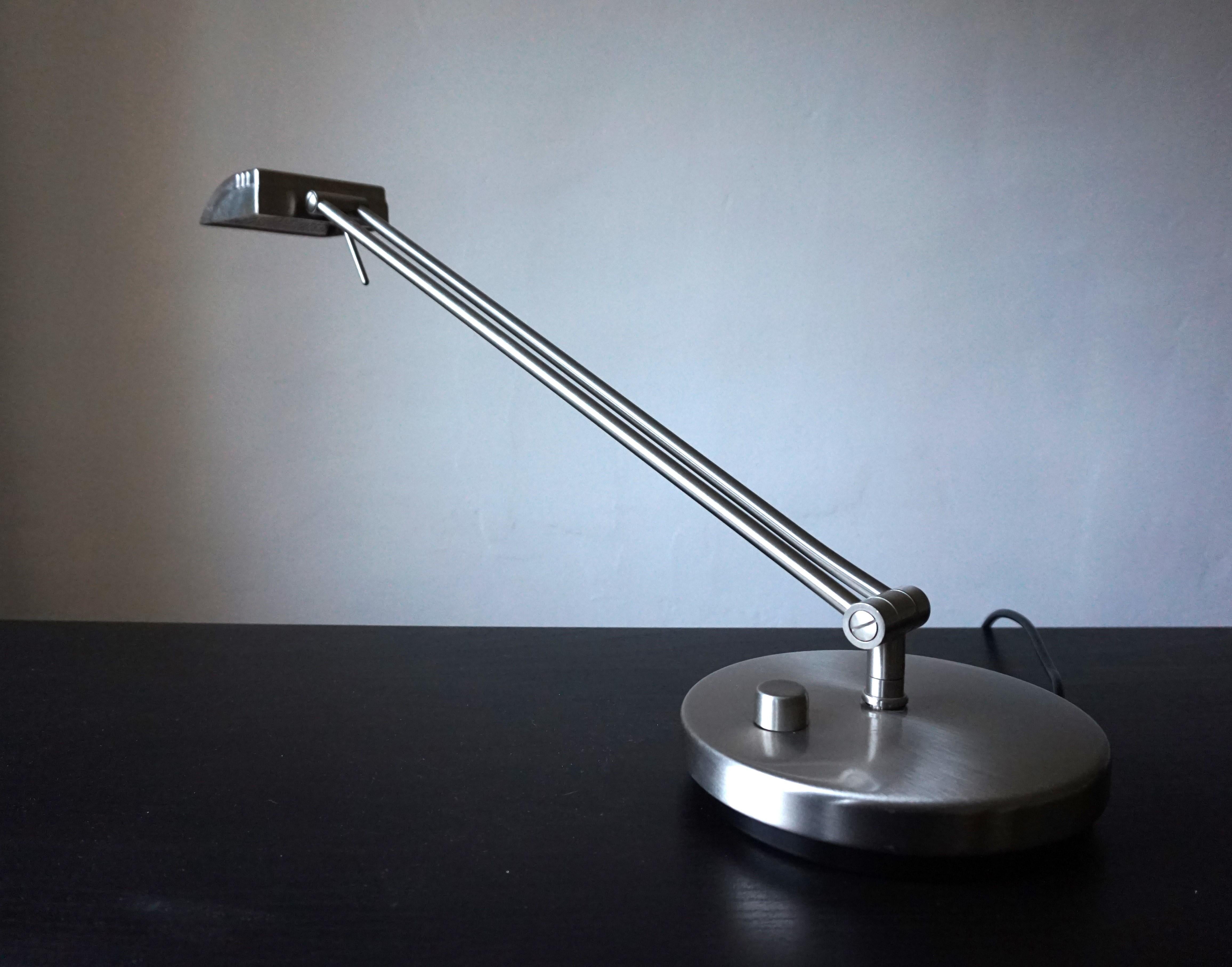 The stainless steel-colored table lamp, whose lines are based on Art Deco designs, is in excellent condition. The heavy lamp can be easily rotated around its own axis and the height of the arm is variable. The angle of the light head can also be
