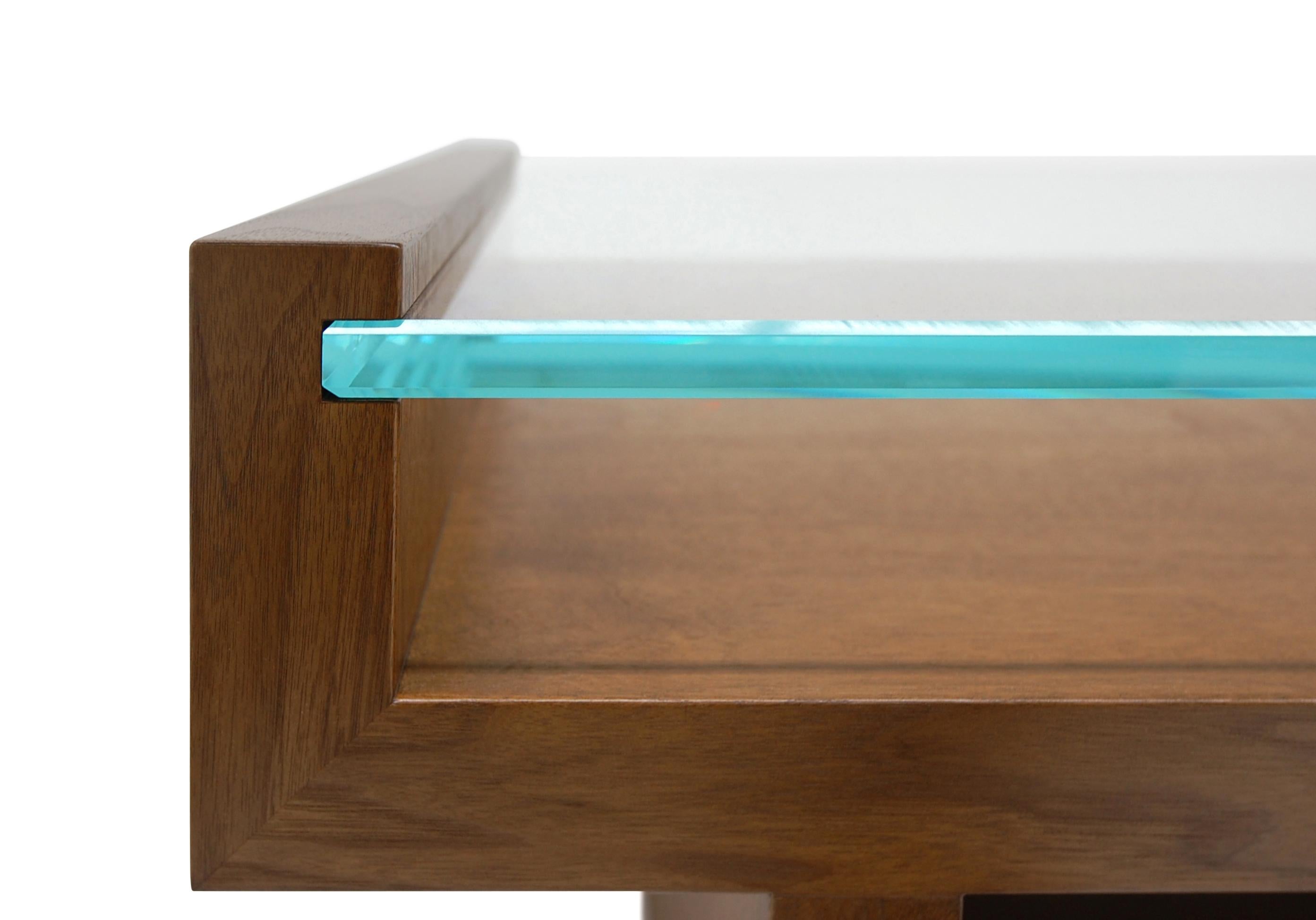 a superbe table Hinge est un équilibre harmonieux entre son plateau en verre élégant et sophistiqué et la solide base en noyer dans laquelle elle est encastrée. Les lignes épurées et les angles forts de cette table basse en font un choix audacieux