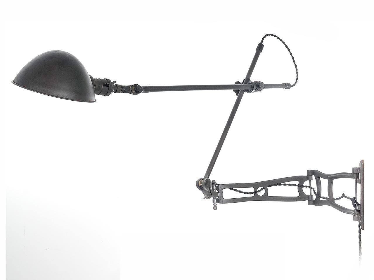 This articulated arm lamp is an O.C. White and its a good one. These lamps have always been sought after by collectors. It has 2 pipe arms using 3 unique style articulating fittings. This is all connected to a hinged cast iron swing outrigger wall