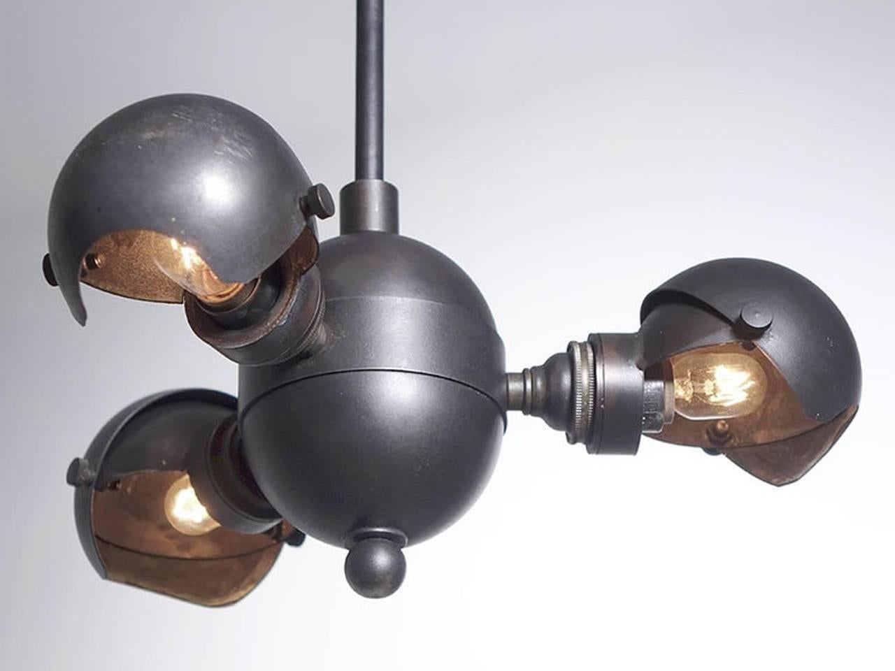 This all brass lamp is totally unique. It was inspired by August Haarstick in the Jugendstil Deco style. There is a centre ball that is the axis for three satellite hinged ball shades. Each hood works as an aperture that pivots to control the amount