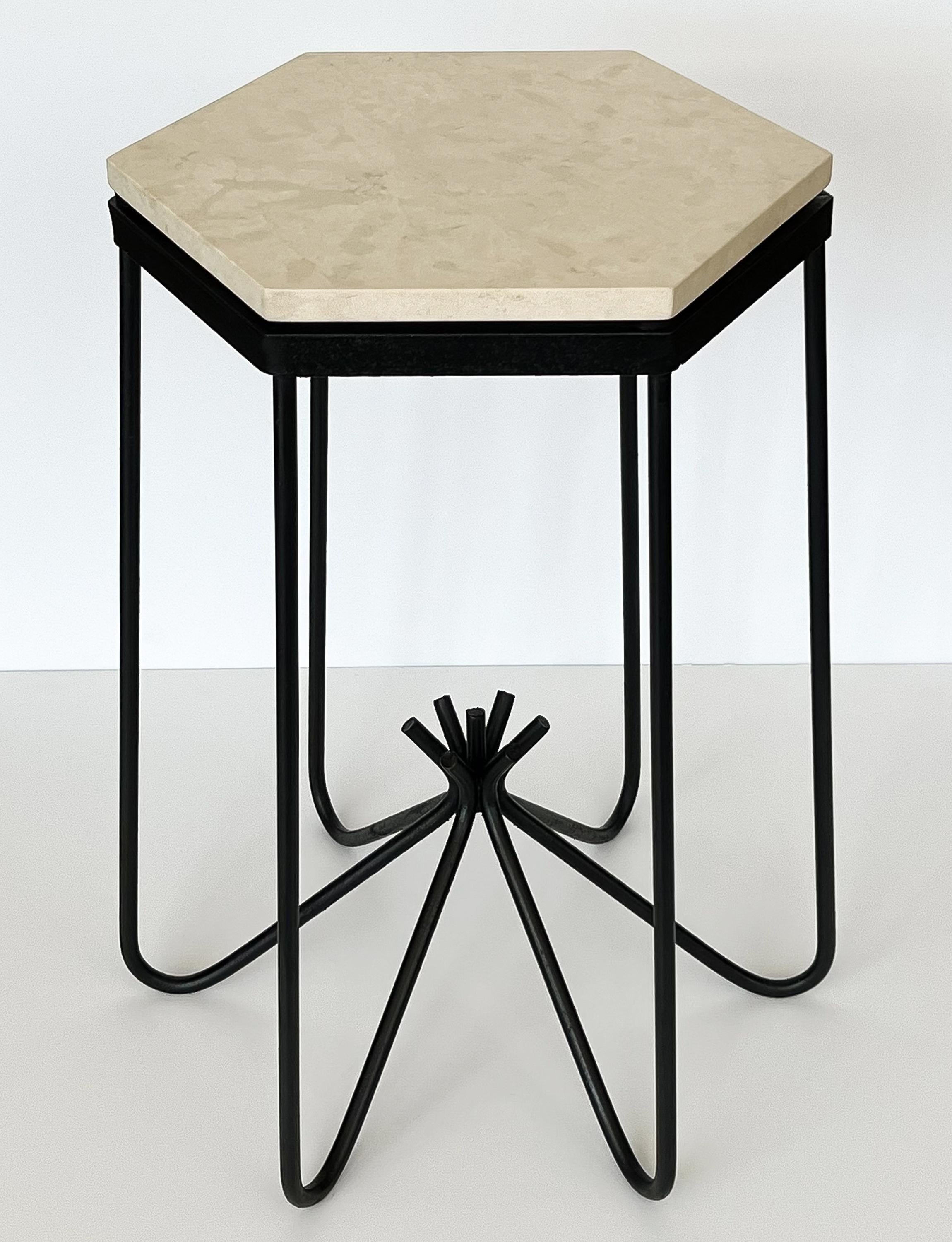 Hirondelle side table in the style of Jean Royère, circa 1950s. This occasional side table or pedestal features a blackened wrought iron framework with a hexagonal cream limestone top. Honed finish to limestone top. Sculptural hairpin base with
