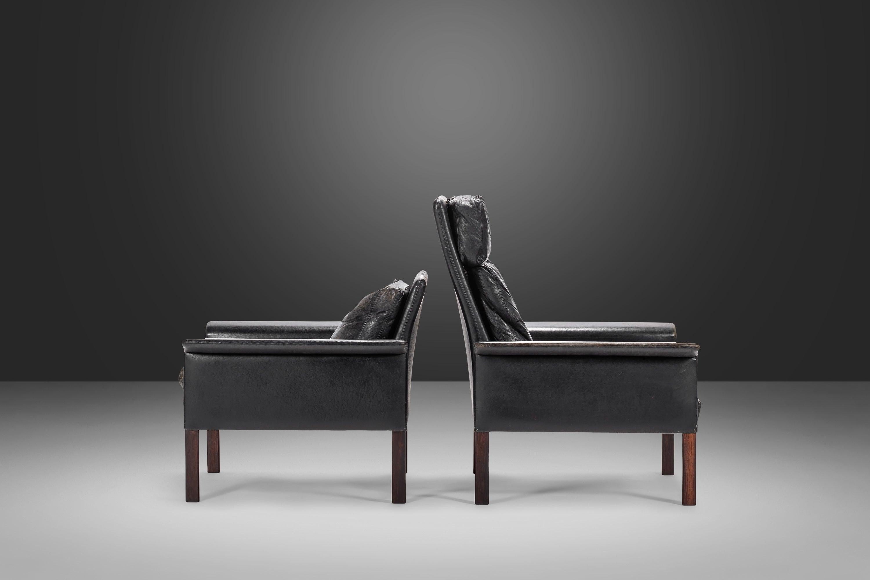 Perfectly worn in black leather and rosewood model #500 his and hers lounge chairs by Hans Olsen for CS Møbler Glostrup made in Denmark. Constructed of solid Brazilian rosewood and original patina'd genuine leather this modern design is
