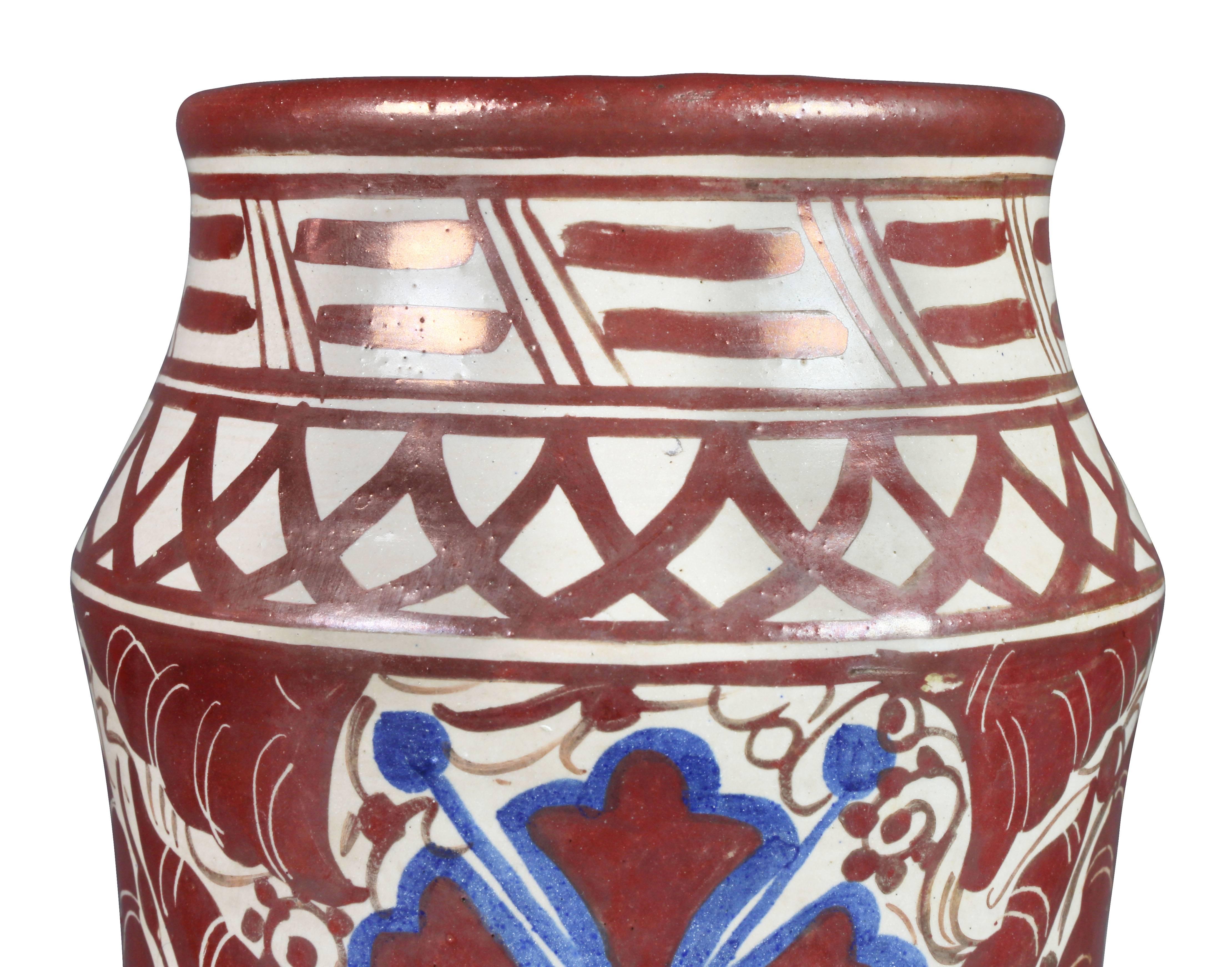 Tall drug jar form with copper red and navy blue decoration on a crème ground. Signed LC in a keyhole shaped cartouche.