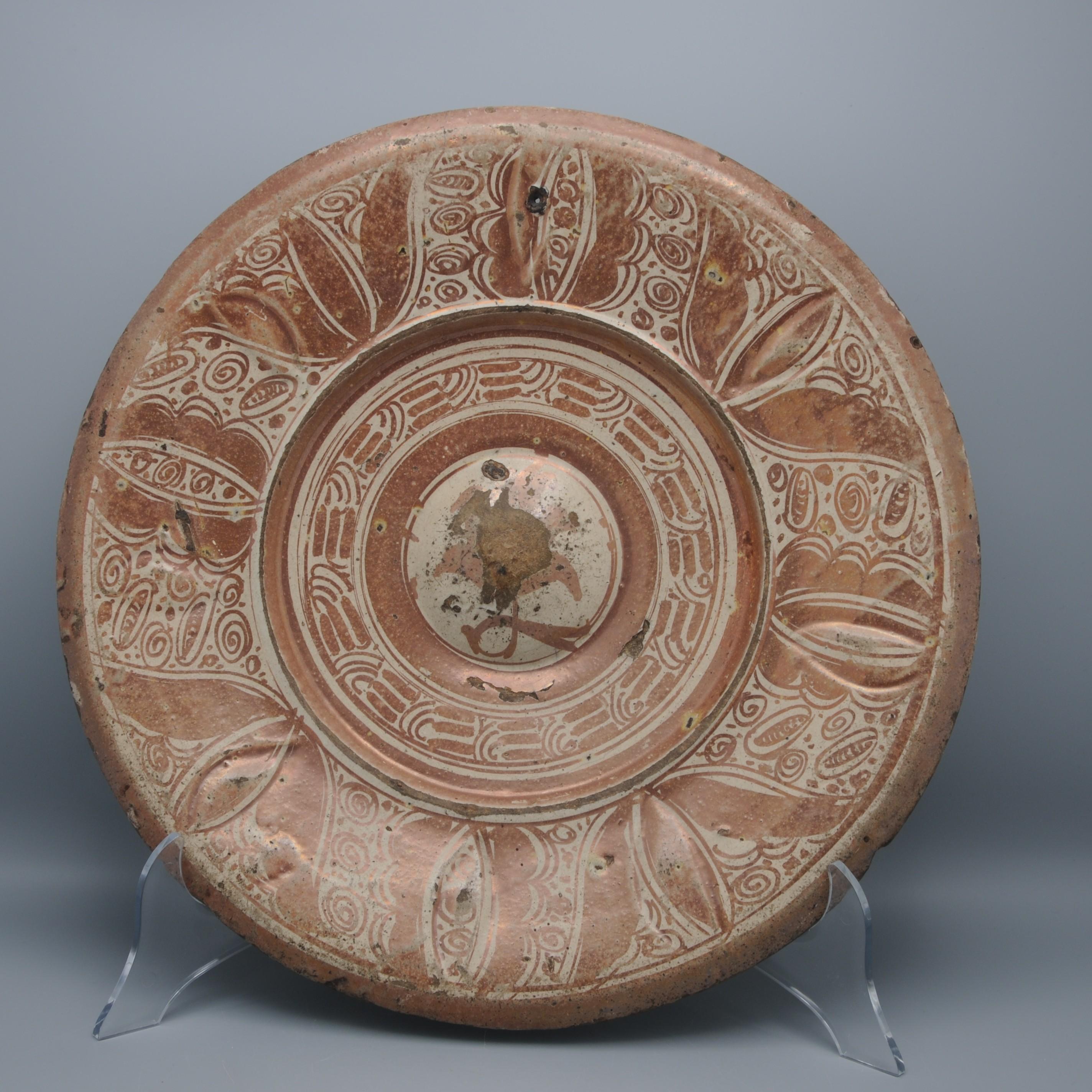 Cargador de loza hispanomorisca del siglo XVI decorado con motivos florales estilizados. 
La cerámica de reflejo metálico vidriada en estaño producida en Sevilla muestra el paso de la influencia artística islámica a la España cristiana.

En buen