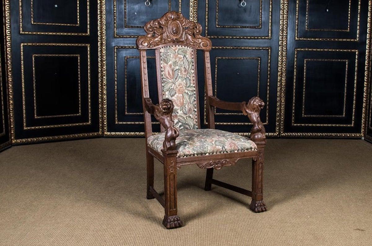 Massive oak. On four legs ending in paw feet, wide seat, flanked by two armrests, with fully plastic lion as a support. Complete with rich carvings. High backrest crowned by sculpted carvings. Seat and back covered with tapestry in Classic design.