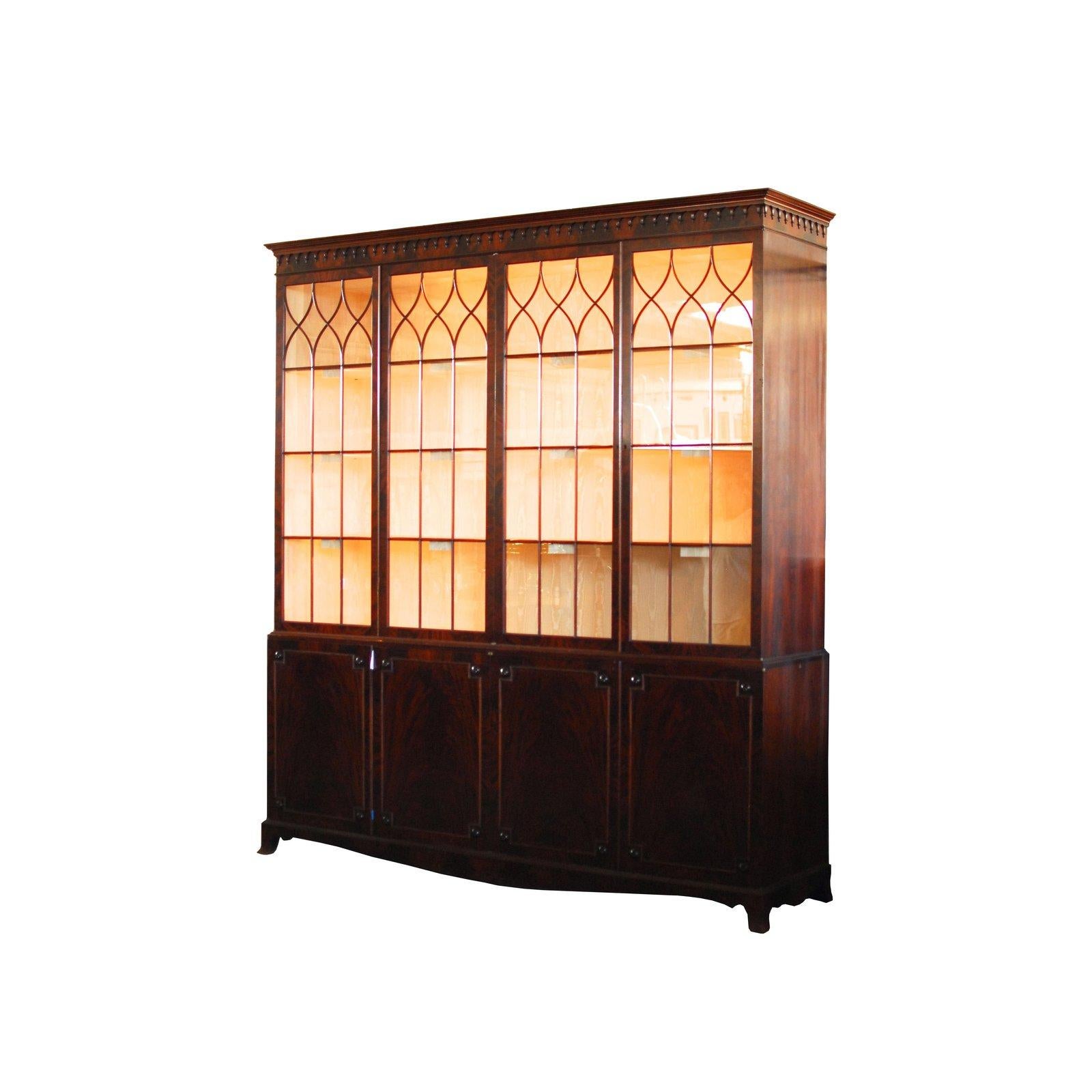Monumental George III mahogany breakfront library cabinet. Massive Gothic Revival style with a four shelf top case that has a modern lighting system with sixteen lights and heavy duty circuits and breaker switches. Fully lined in a silk fabric and