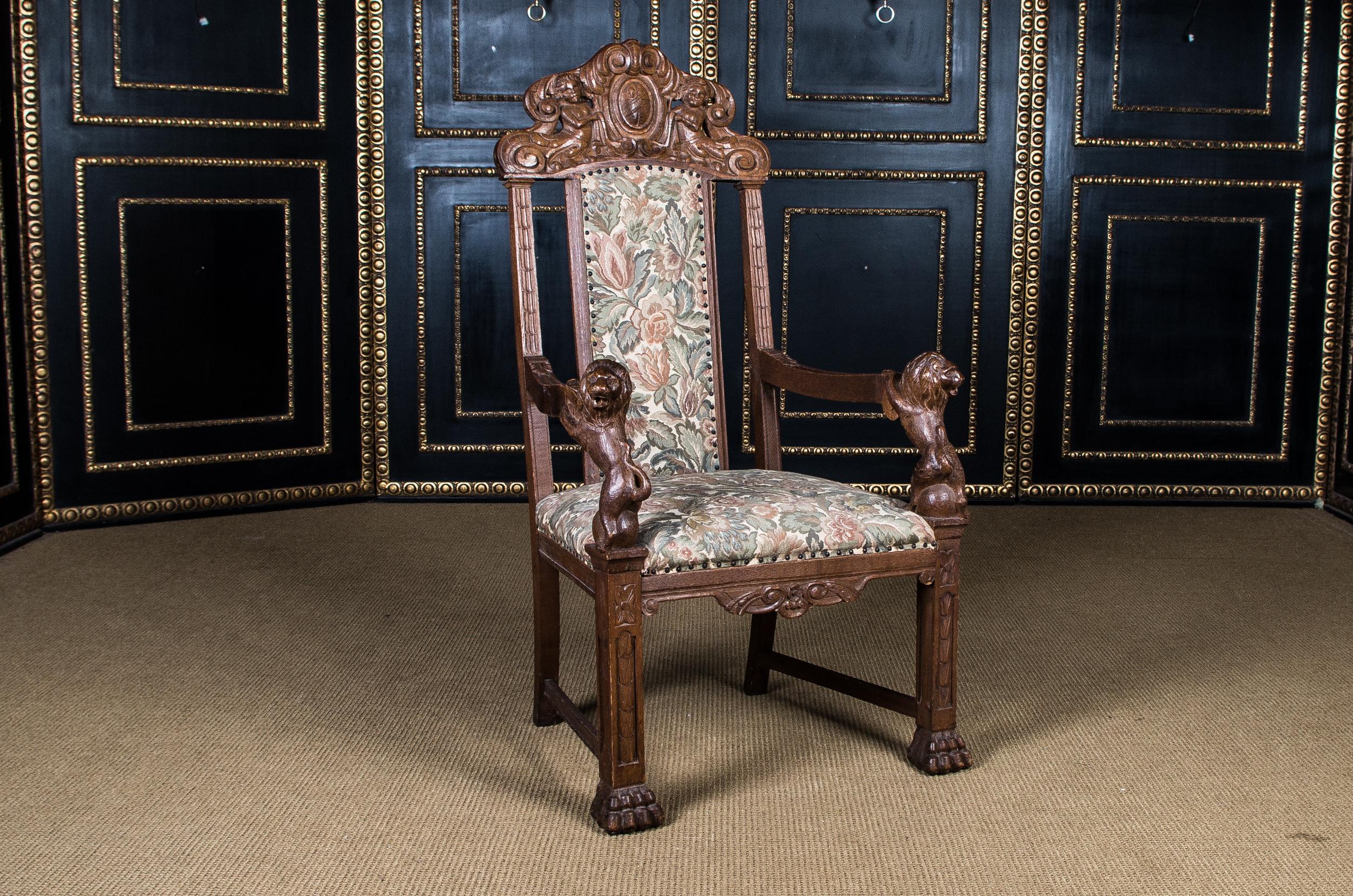 Massive oak. On four legs ending in paw feet., wide seat, flanked by two armrests, with fully plastic lion as a support. Complete with rich carvings. High backrest crowned by sculpted carvings. Seat and back covered with tapestry in Classic