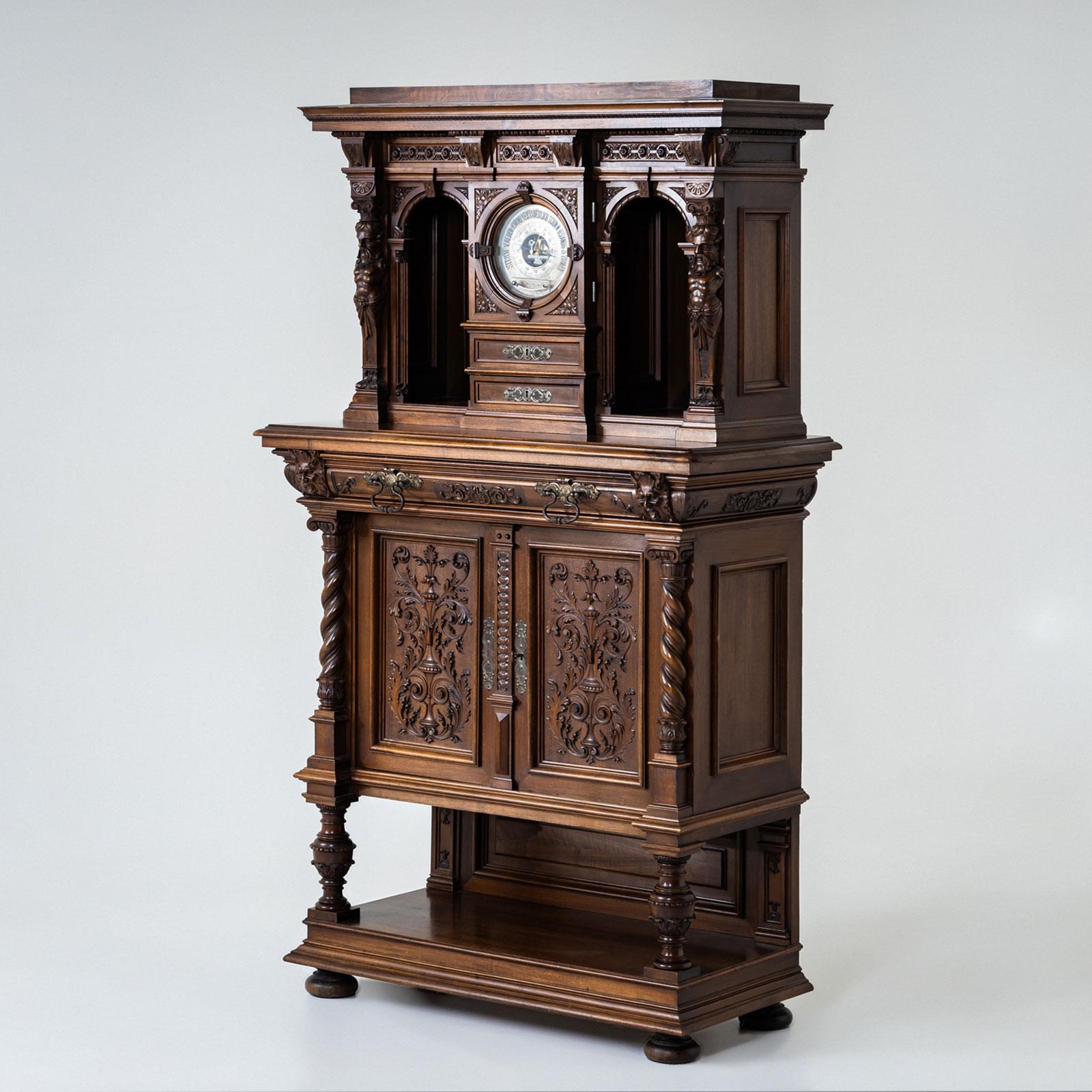 Un imponente mobile del periodo storicista, realizzato in Germania alla fine del XIX secolo. La parte inferiore presenta due ante e un ampio cassetto, riccamente ornati da intricate decorazioni intagliate, semicolonne tornite e gambe a balaustro