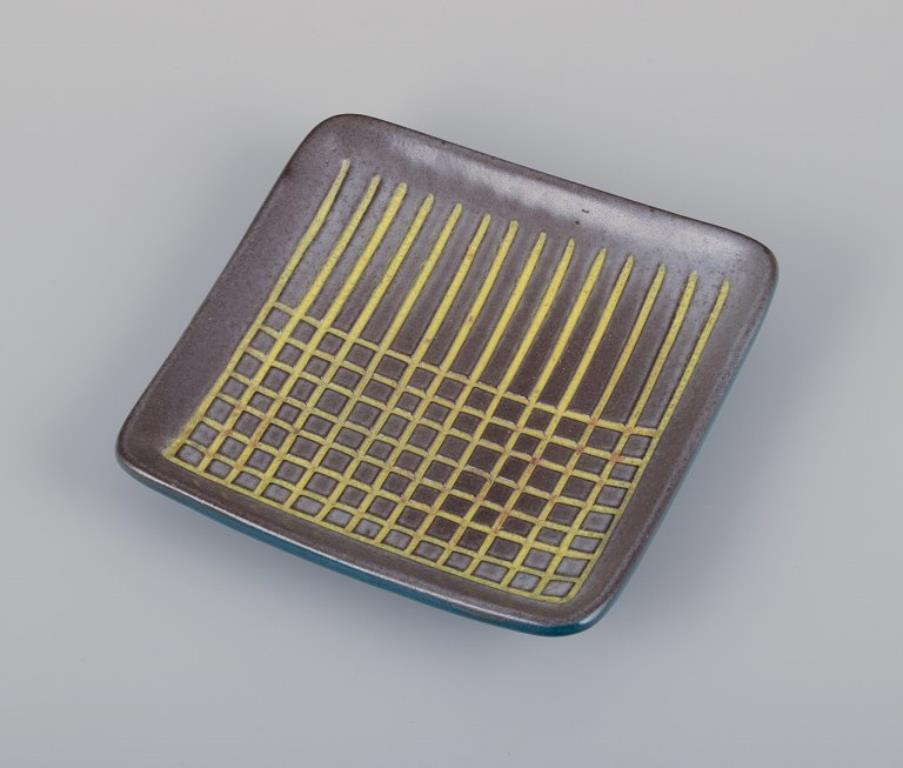 Hjördis Oldfors (1920-2014) for Upsala Ekeby. 
Ceramic tray with glaze in yellow, brown, and blue tones. Geometric pattern.
From approximately the 1960s.
Marked.
In perfect condition.
Dimensions: 15.0 cm x 15.5 cm x 3.0 cm.