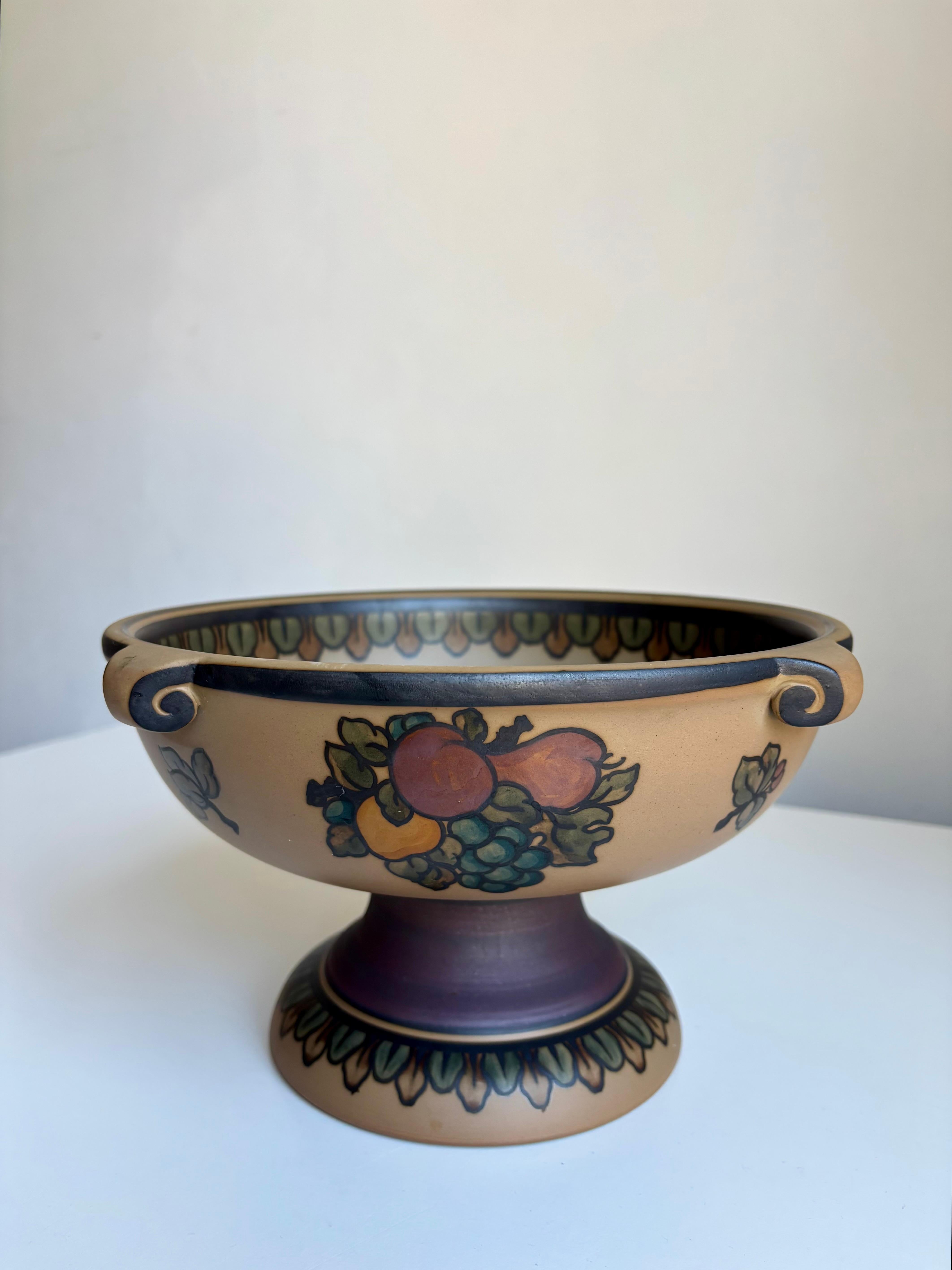 Jugendstil-Terrakotta-Sockelschale aus den 1940er Jahren mit handgemaltem, naturalistisch-organischem Dekor mit bunten Früchten und Beeren auf sandbraunem, mattem Sockel. 
Hergestellt von der L. Hjorths Terracottafabrik in der kleinen Stadt Rønne