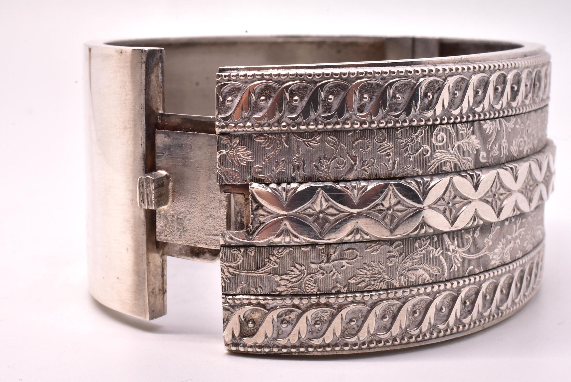 Our silver bangle is decorated with a five bands of repeating patterns of arabesques and scrolls. The center band , with its repeating X's, represent kisses. The Victorians loved geometric patterns, and silver bangles, brooches and the like were