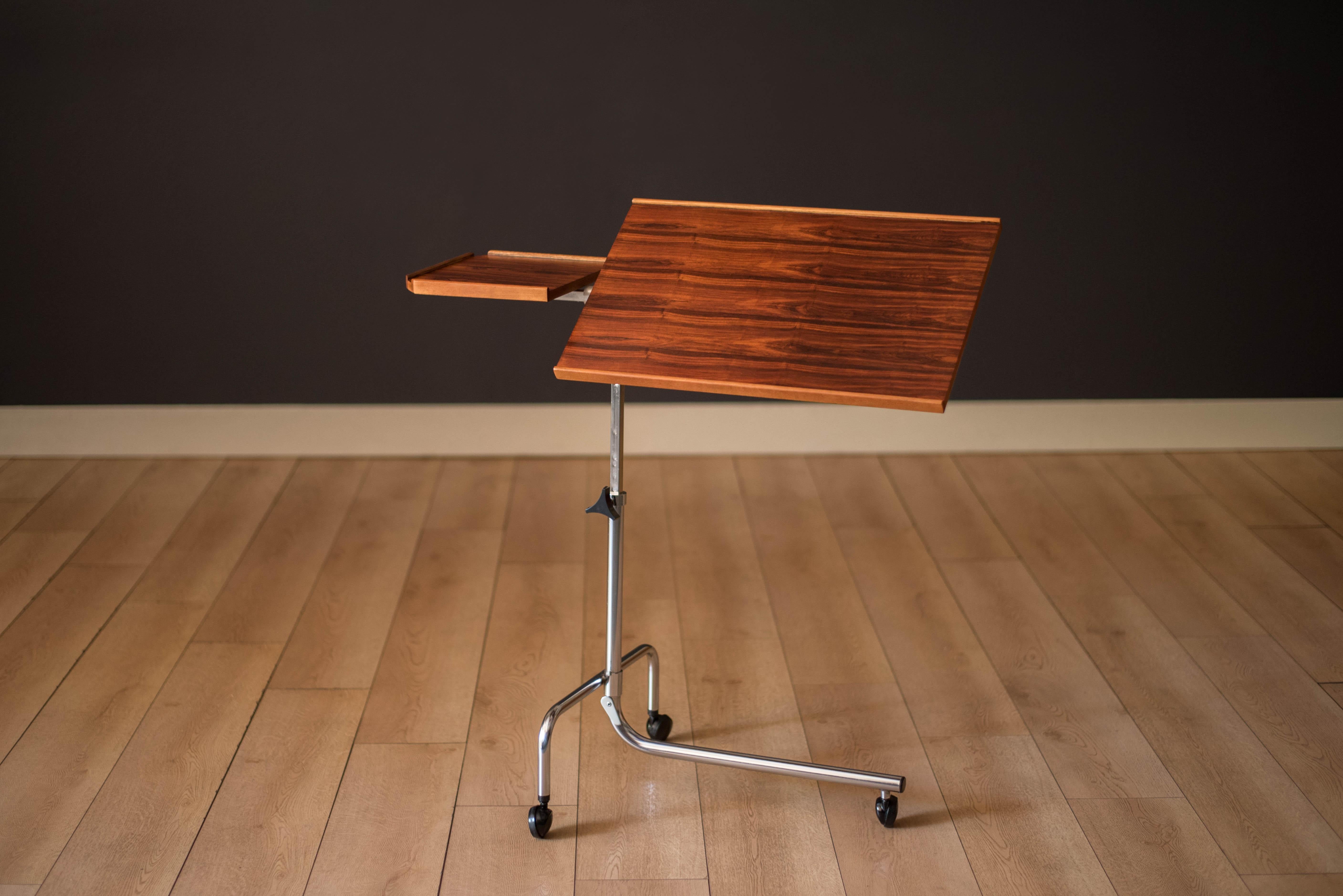 Mid-Century Modern ergonomic bedside reading stand in rosewood and chrome manufactured by H.M.N., Denmark circa 1970s. Features a tilting tray and a small fixed table designed with sculptural raised edges to catch pens or small accessories. The