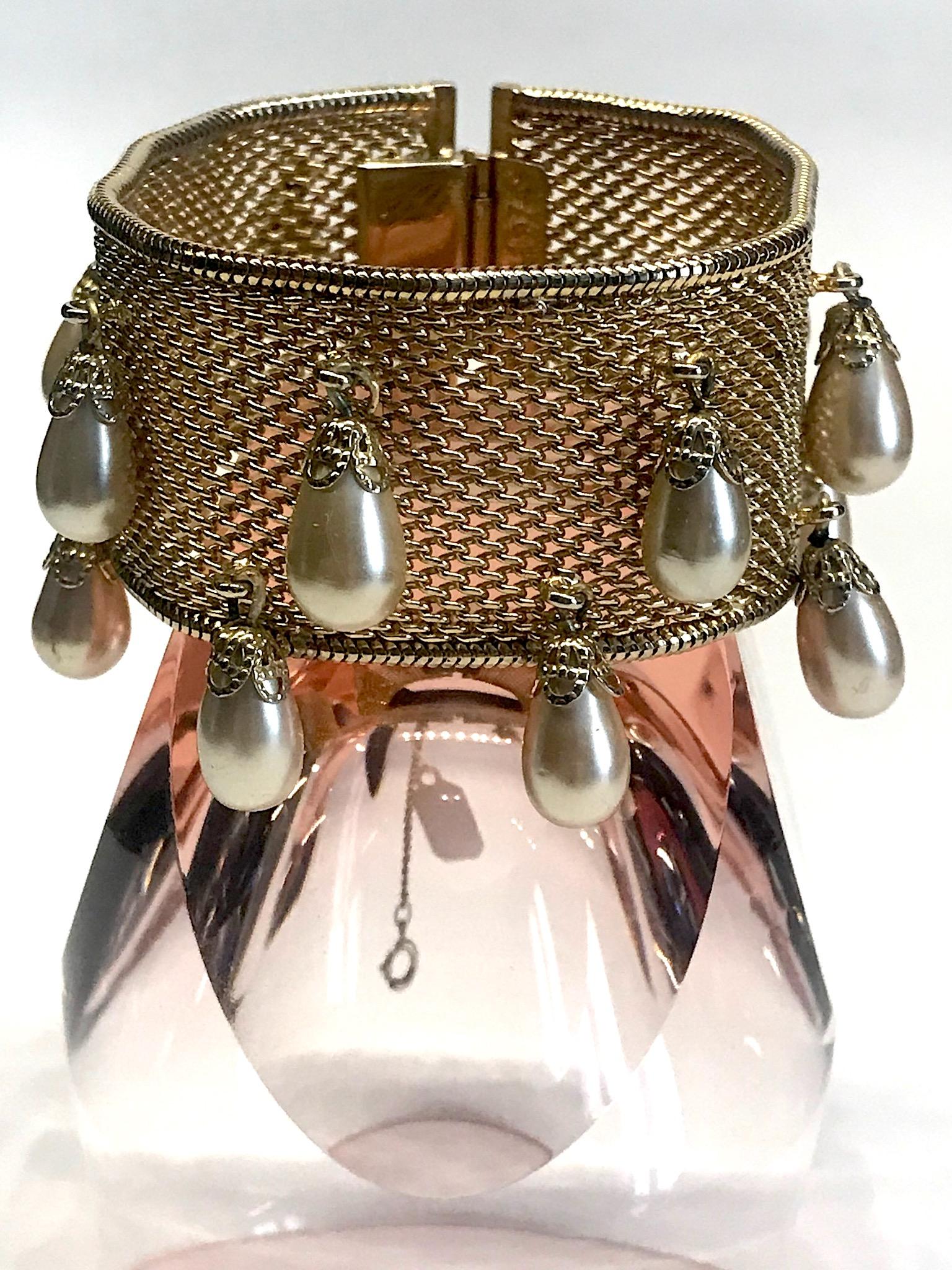 A wonderful vintage Hobe' woven mesh bracelet with pear dangles from the 1950s. The woven band is bordered on both sides with a snake link finish. There are 14 creamy champagne color and pear shape faux pearl bead dangles. Each pearl is set into a