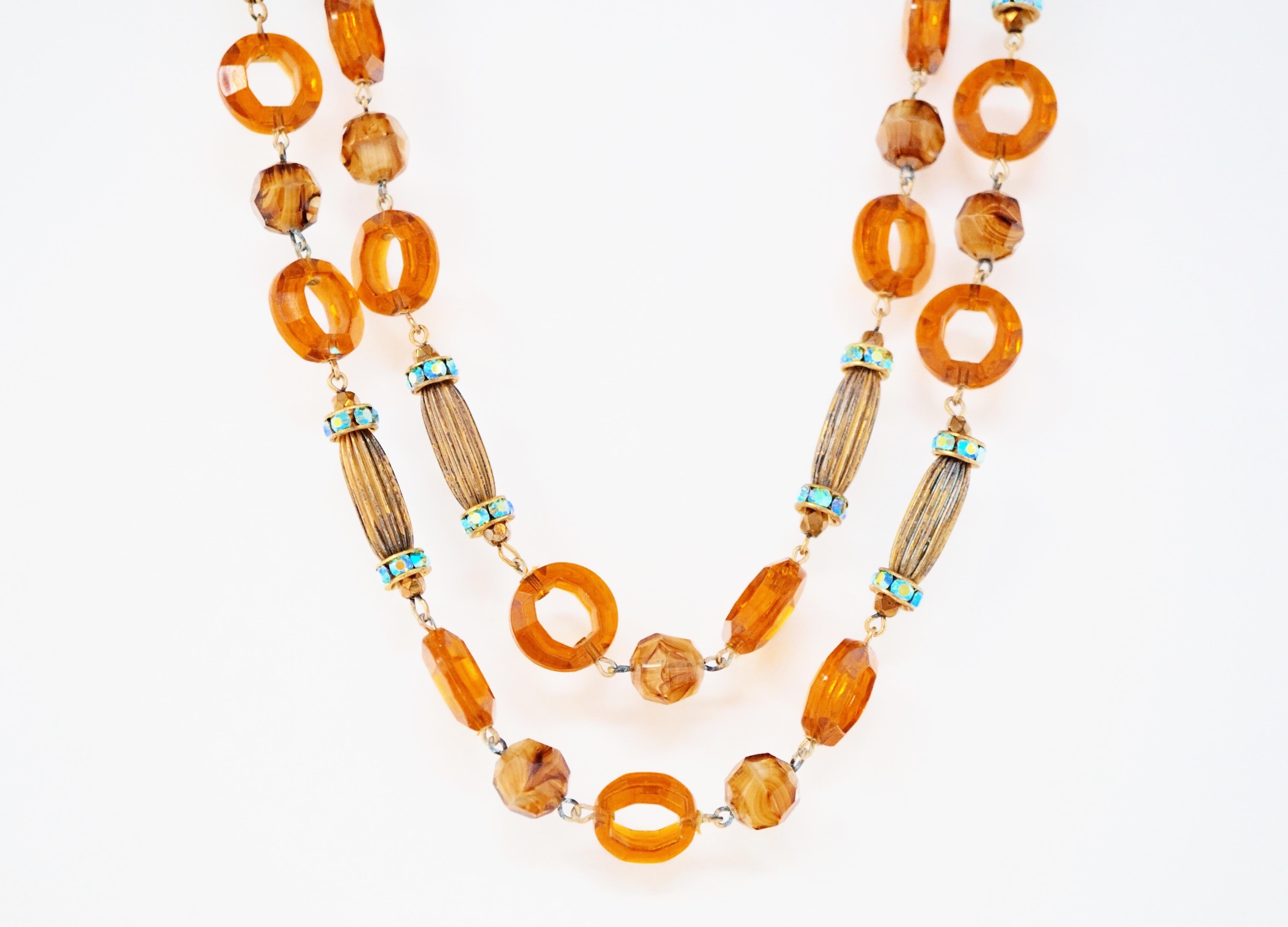 Diese wunderschöne doppelreihige Hobé-Halskette aus den 1960er Jahren zeichnet sich durch ein Muster aus orangefarbenen, durchscheinenden Ringperlen, antiken messingfarbenen Röhrenperlen und babyblauen Aurora Borealis Swarovski-Kristallrondellen