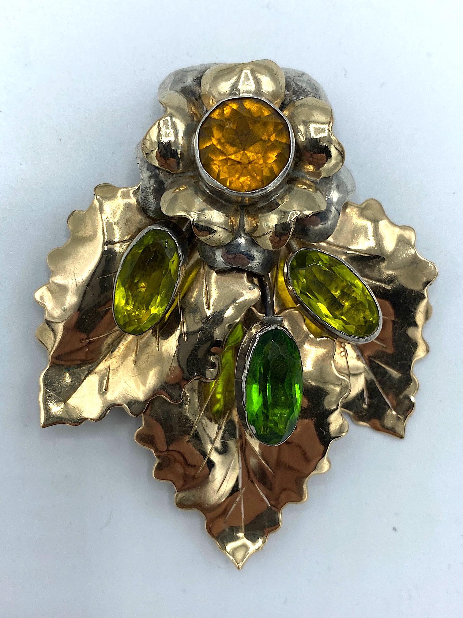 

A beautiful sterling silver floral brooch by jewelry company Hobe' and made between 1941 and 1948. The brooch is hand soldered with a three dimensional top flower in sterling silver and a central bezel set gold gold crystal stone. Extending down