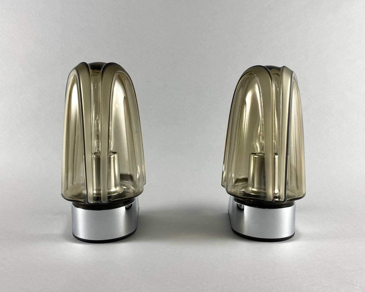 Pair Of Stylish Designer Wall Lamps
by Hoffmeister Leuchten, Germany.

Each vintage sconce consists of one designer horn made of high quality plastic. The lampshade of the wall lamp is made of smoky glass decorated with a relief pattern.

 Wall