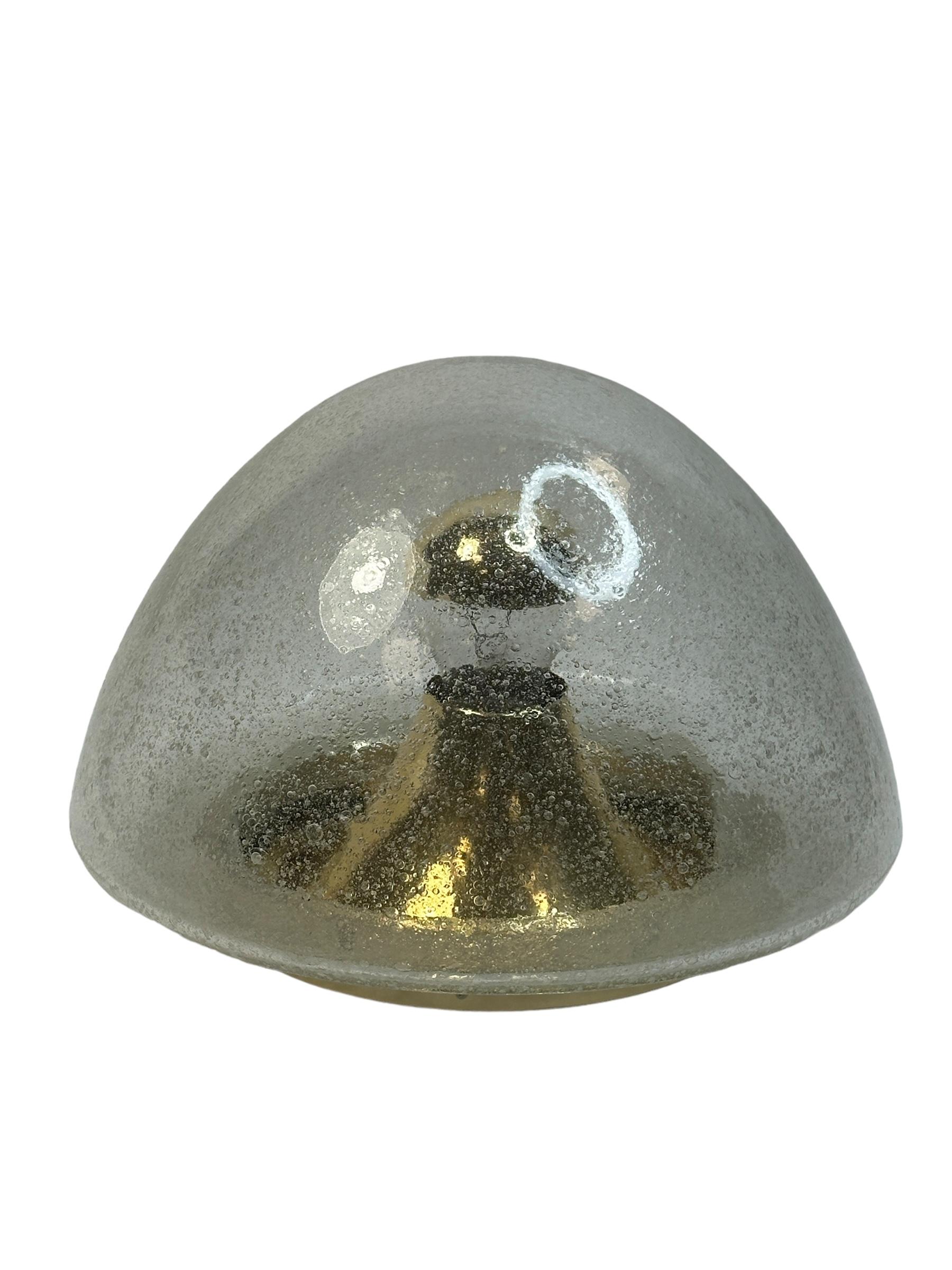 A gorgeous futuristic glass flush mount by Hoffmeister Leuchten. It can be used also as a wall light. The Fixture requires an European E27 / 110 Volt Edison bulb, up to 60 watts. Clear Murano glass with lots of little air bubbles, mounted on a brass