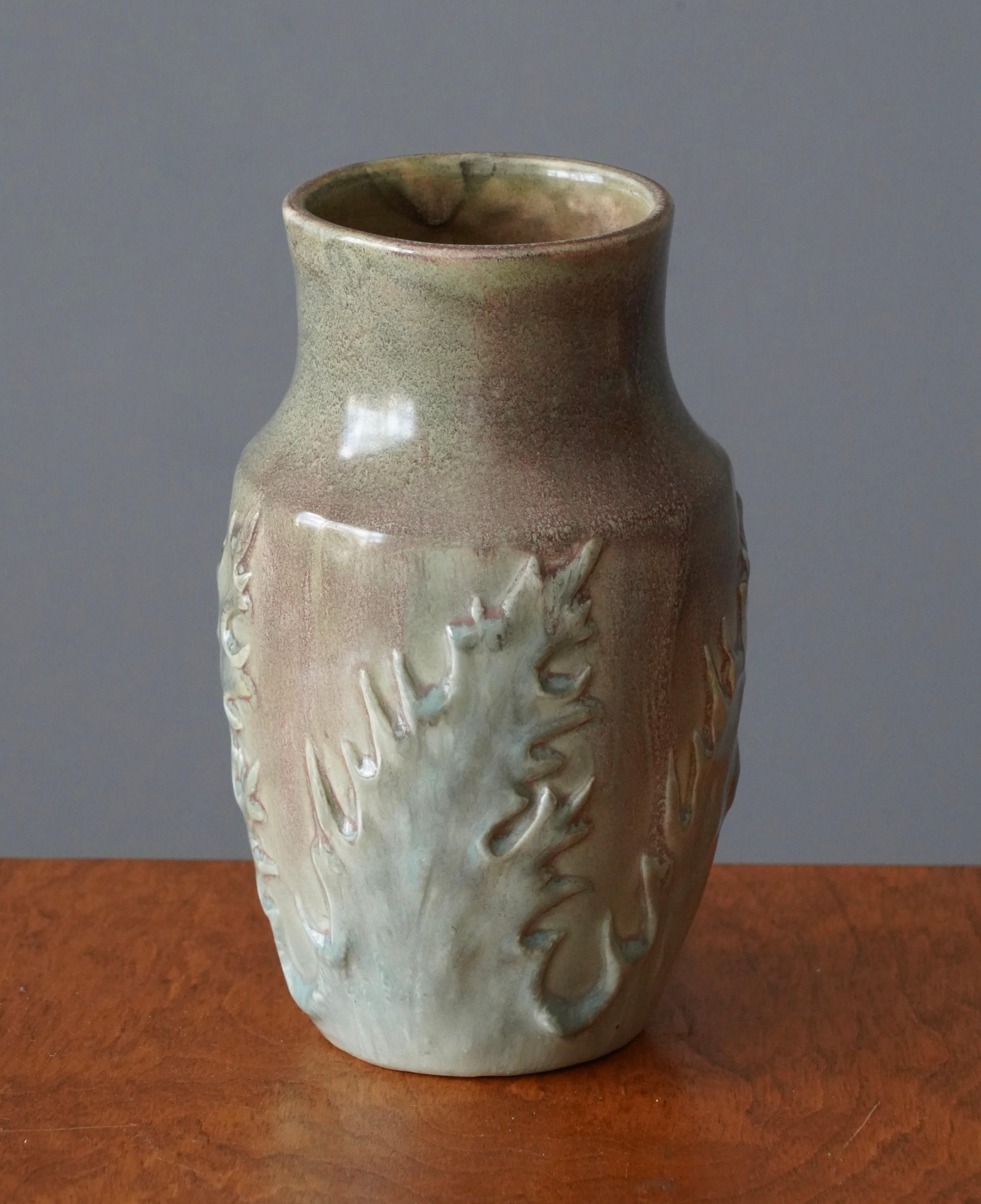 A vase, designed and produced by Höganäs Keramik, Sweden, 1920s. Features floral relief motifs. In green and blue tones.

In earthenware with highly artistic glaze in grey and beige.