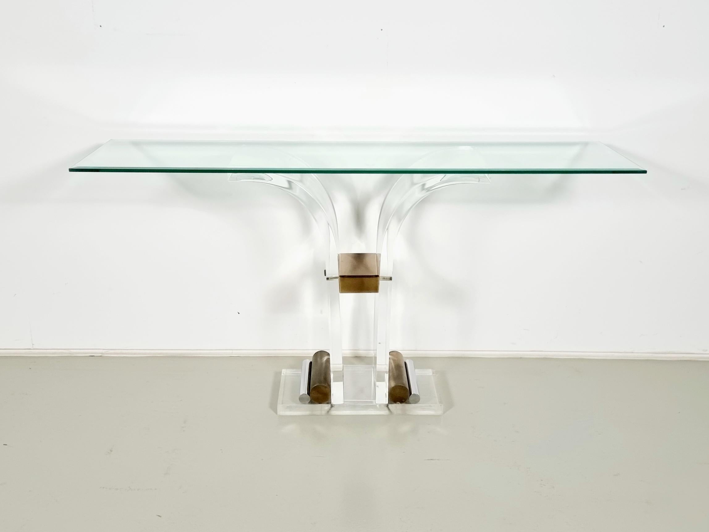 Table console en lucite, laiton et verre de Charles Jones, vers 1970. Magnifique base en lucite épaisse avec des détails en métal et un design sculpté avec un plateau en verre taillé. 

Tout est d'origine et en très bon état. Le verre repose sur la