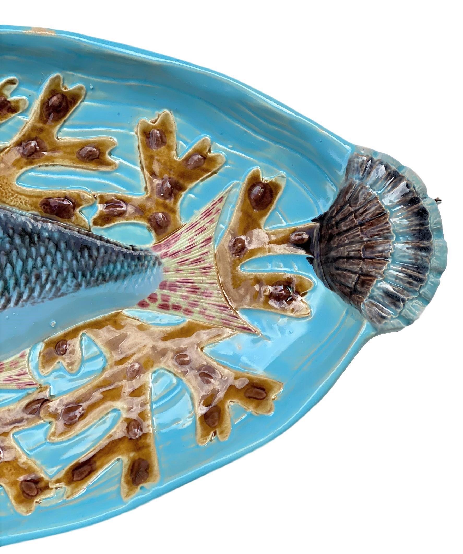 Holdcroft Majolica 7-piece salmon service, English, circa 1875, including a platter, naturalistically molded as a salmon on a bed of seaweeds; on a molded ground simulating moving water, glazed in turquoise blue, with shell form handles molded in