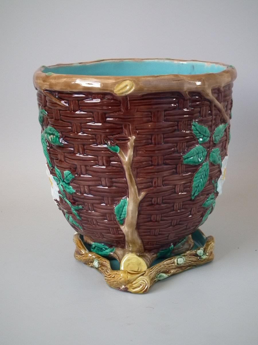 Holdcroft Majolica jardinière and stand which features a basket weave exterior with dog rose blossom and leaves. Colouration: brown, green, turquoise, are predominant. The piece bears maker's marks for the Holdcroft Pottery. Bears a pattern number,