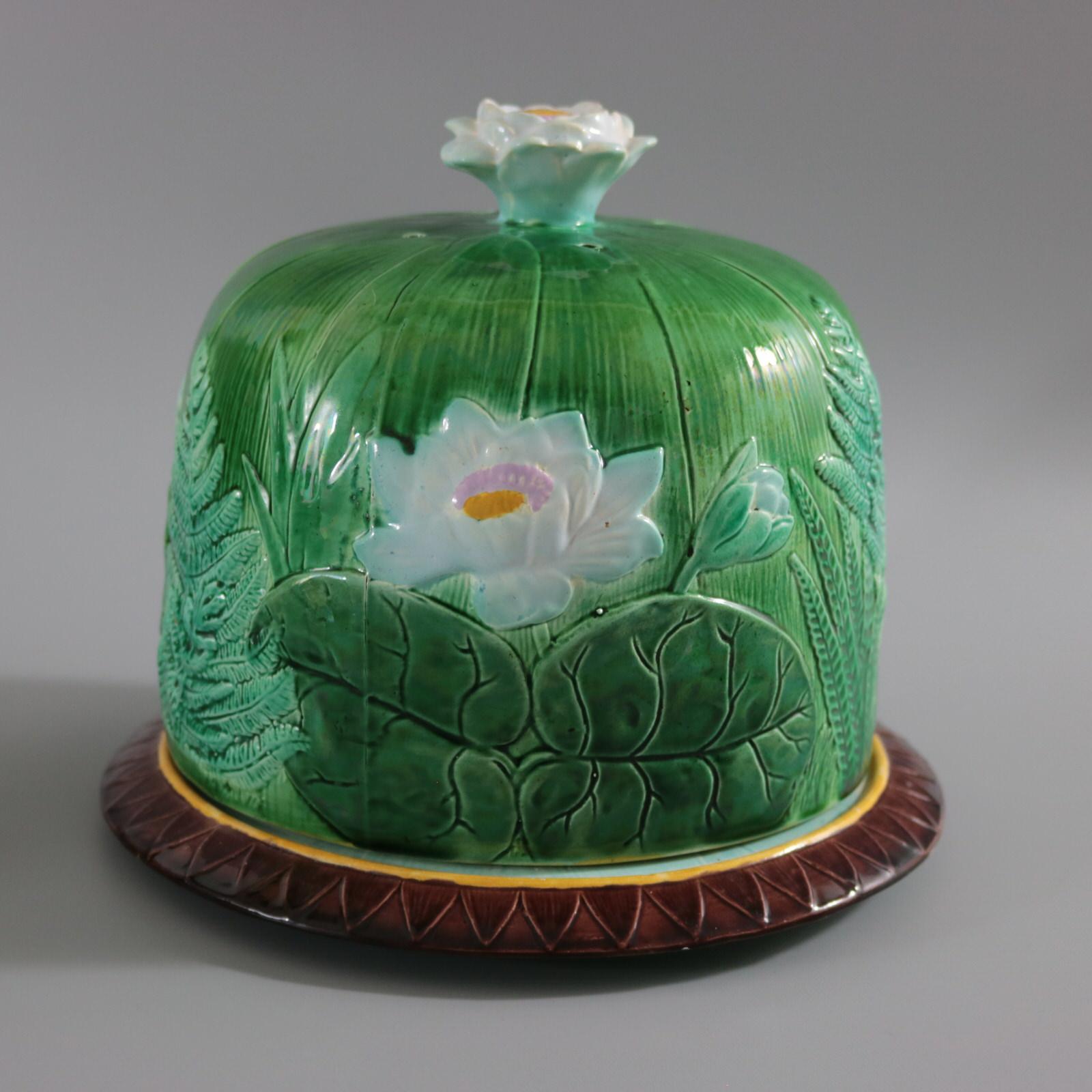 Holdcroft Majolica cheese keep which features fern fronds, and pond lily leaves and flowers. Colouration: green, white, brown, are predominant. The piece bears maker's marks for the Holdcroft pottery. Bears a pattern number, '36'. Book reference