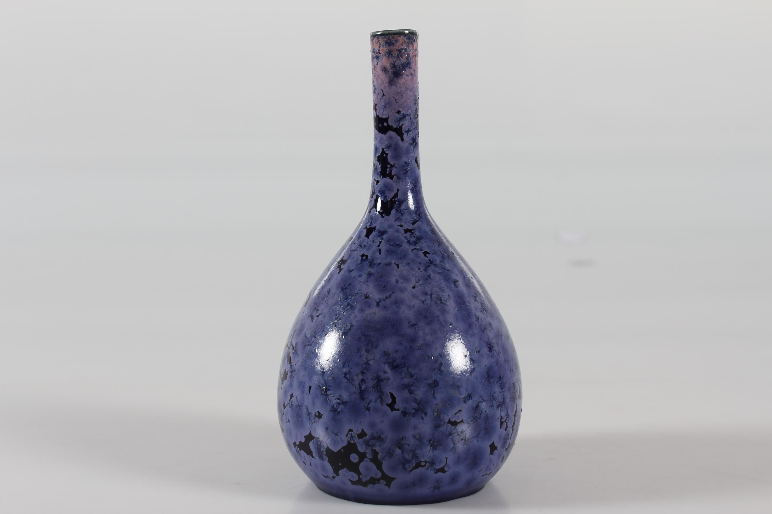 Drop-shaped vase with slender slim neck designed by Holger Busch Jensen for the Danish porcelain manufacturer Bing & Grøndahl. Made in the beginning of the 20th century.

The vase is glazed with crystal glaze in shades of lilac and purple.

Mint