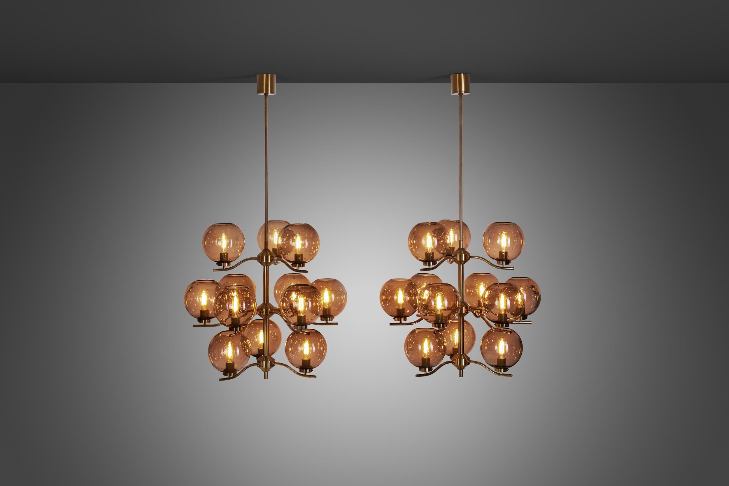 This marvellous pair of chandeliers is a rarity from Swedish designer, Holger Johansson, who created them for his own company, Westal. With a brass frame holding 12 translucent bubble glass shades, grandiose and stylish are the words to describe