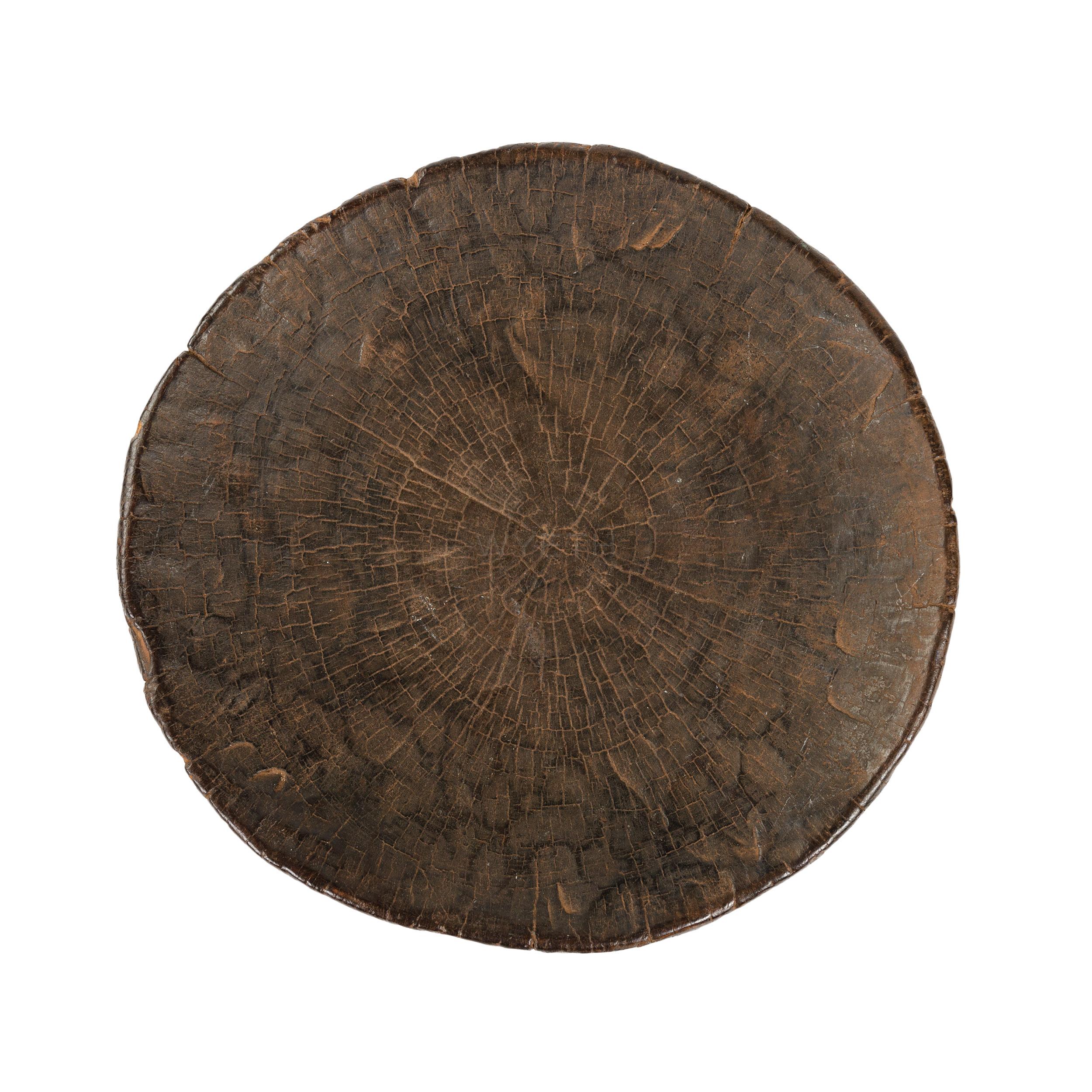 A stool carved from a hollowed-out log section, with a rectangular piercing bisected by a diamond-shaped head motif.