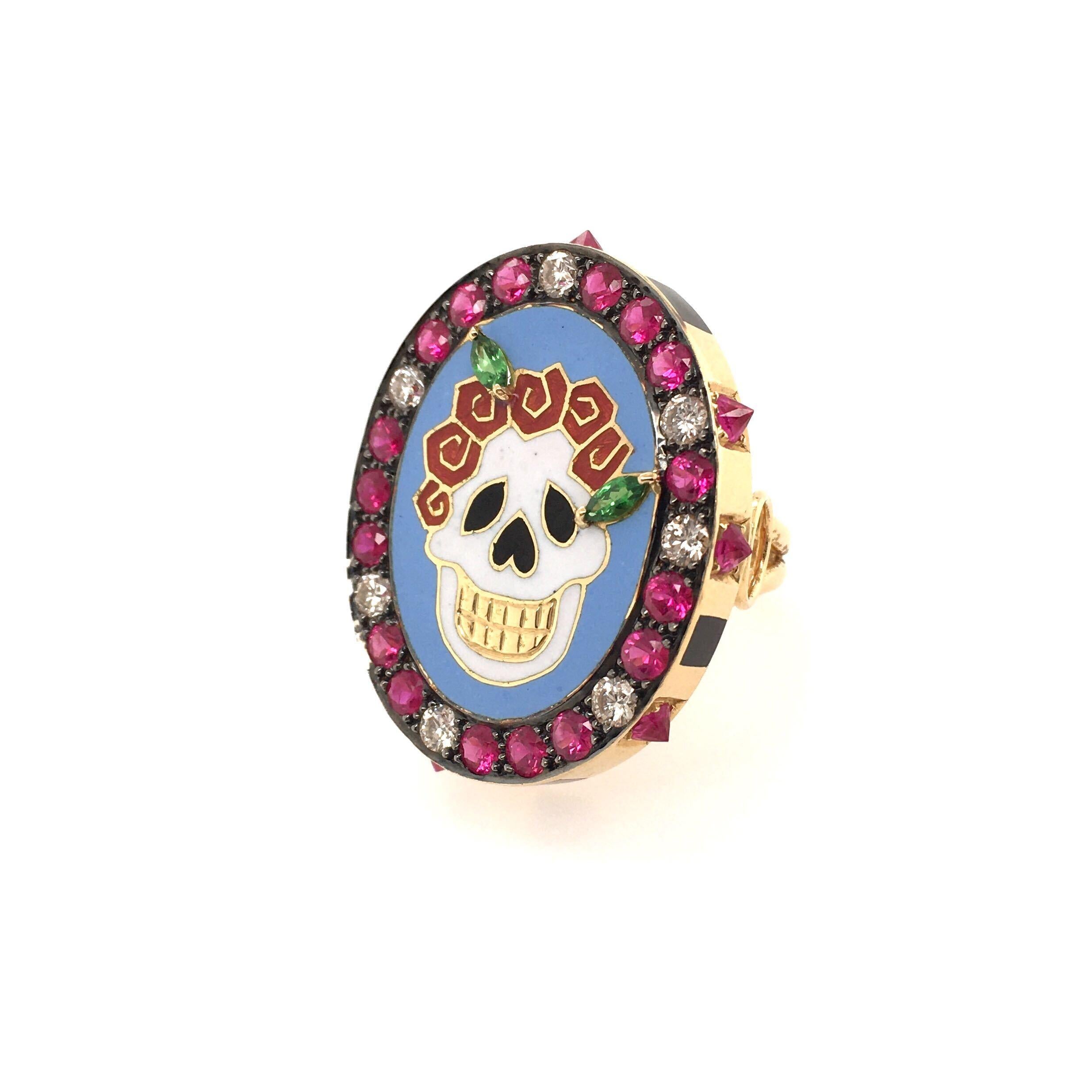 An 18 karat yellow gold, enamel and gemset Skull ring. Holly Dyment. Designed as an white, cream and black enamel skull, against a light blue background, wearing a crown of red flowers, enhanced by tsavorite garnet leaves, within a circular cut ruby